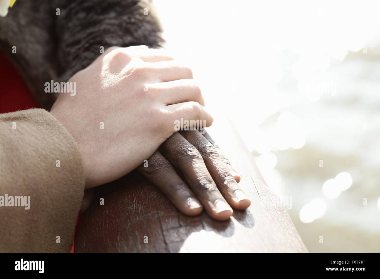 Multi Ethnic couple outdoors, man resting hand on woman's hand, close-up Banque D'Images