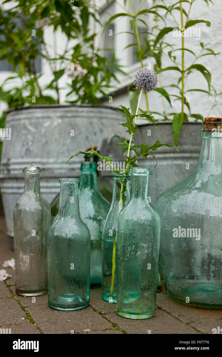 Vintage tin pots et bouteilles sur terrasse dans la pluie Banque D'Images