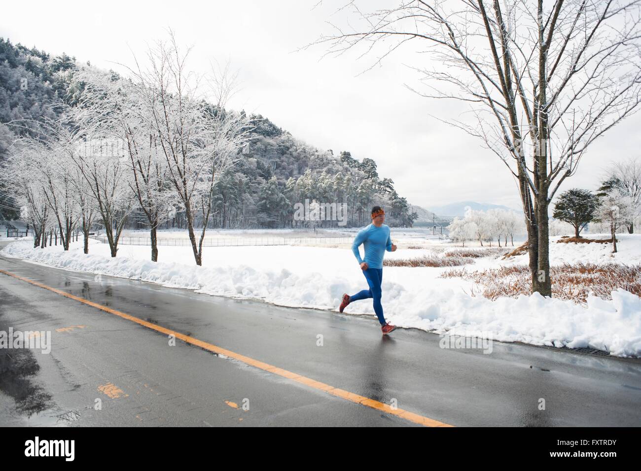 Mâle mature runner s'exécutant sur route en hiver, le lac Kawaguchiko, le Mont Fuji, Japon Banque D'Images