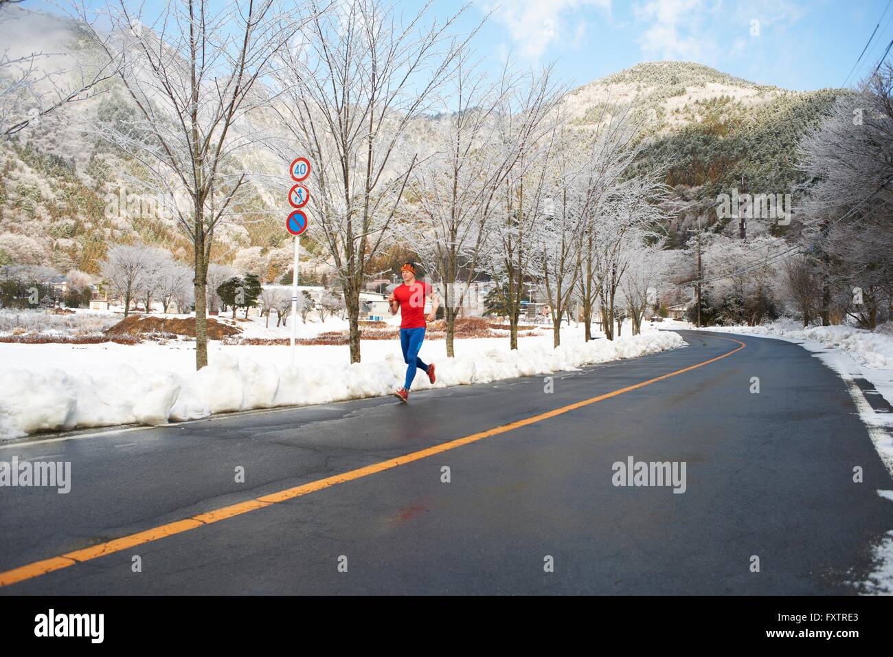 Coureur mâle s'exécutant sur route en hiver, le lac Kawaguchiko, le Mont Fuji, Japon Banque D'Images