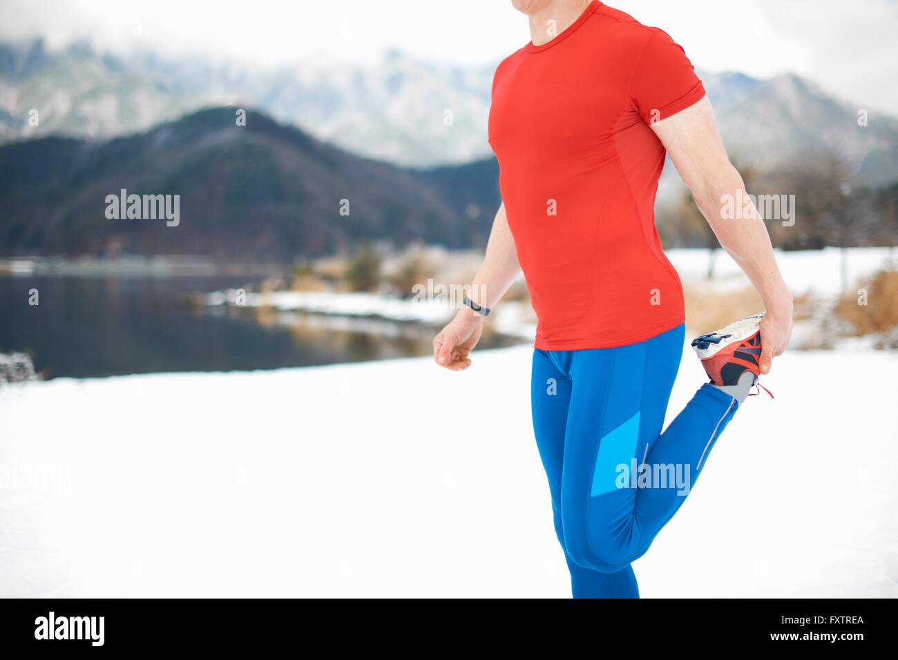 Vue latérale du coureur masculin par jambe s'étendant du lac couvert de neige, le lac Kawaguchiko, le Mont Fuji, Japon Banque D'Images