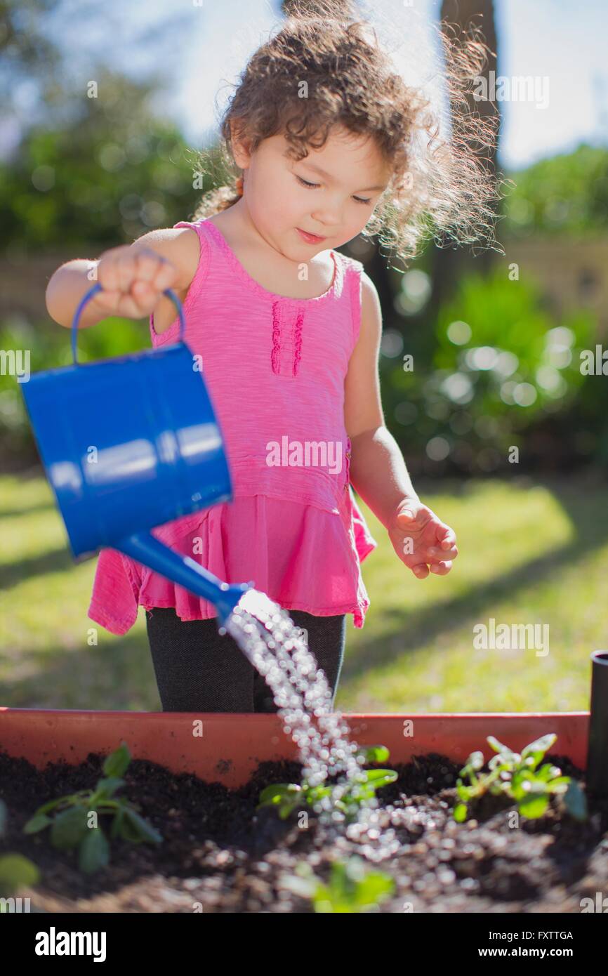 Jeune fille au jardin, holding watering can, l'arrosage des plantes en pot Banque D'Images