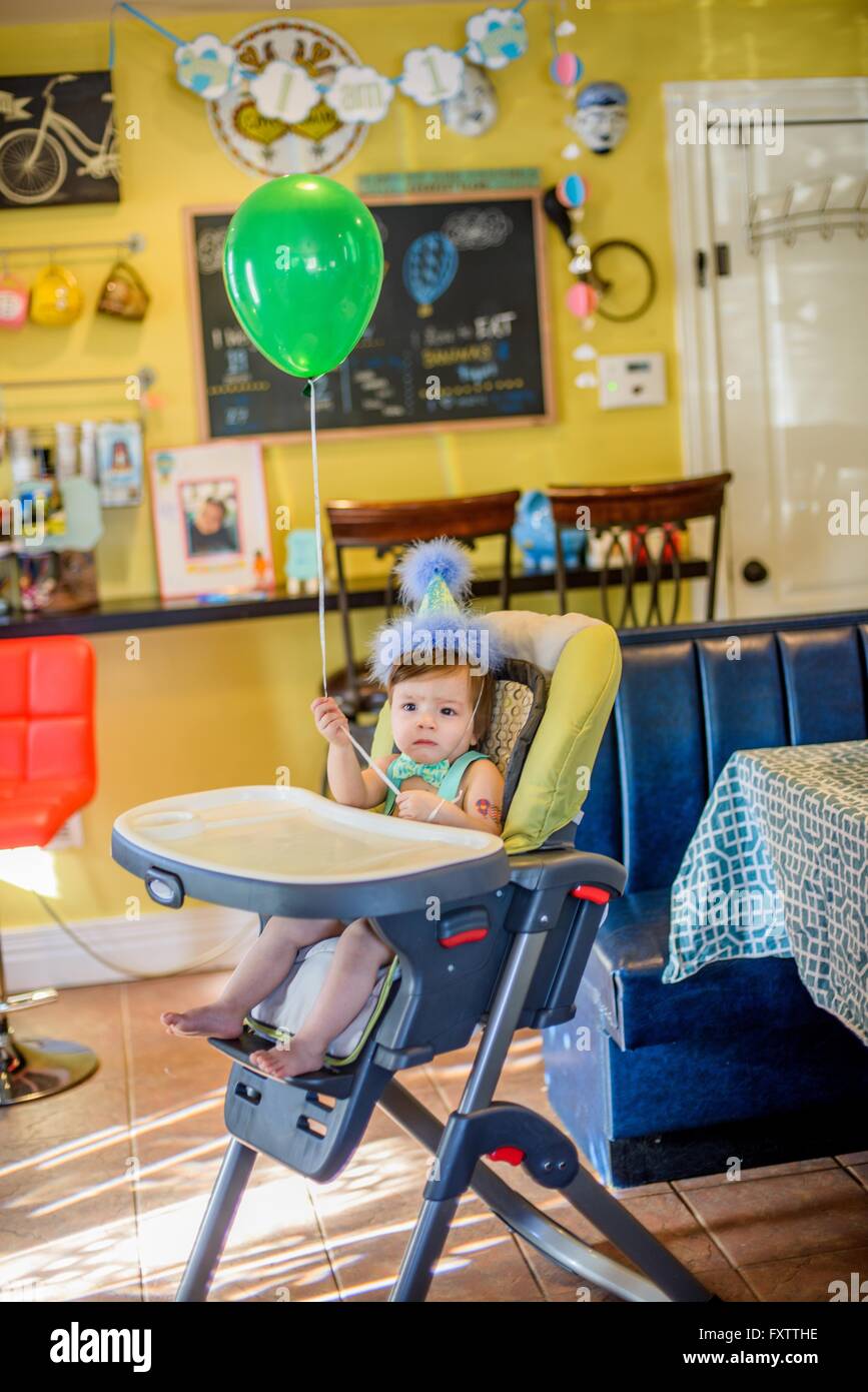 Portrait of baby boy wearing Birthday party hat assis dans une chaise haute Banque D'Images