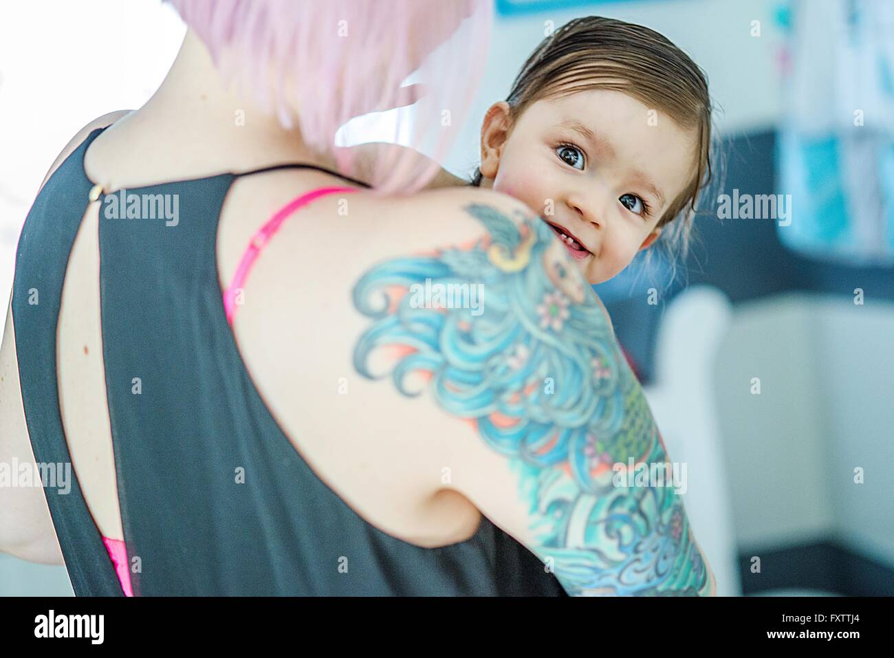 Portrait de bébé garçon jeter par-dessus son épaule tattoed mères Banque D'Images