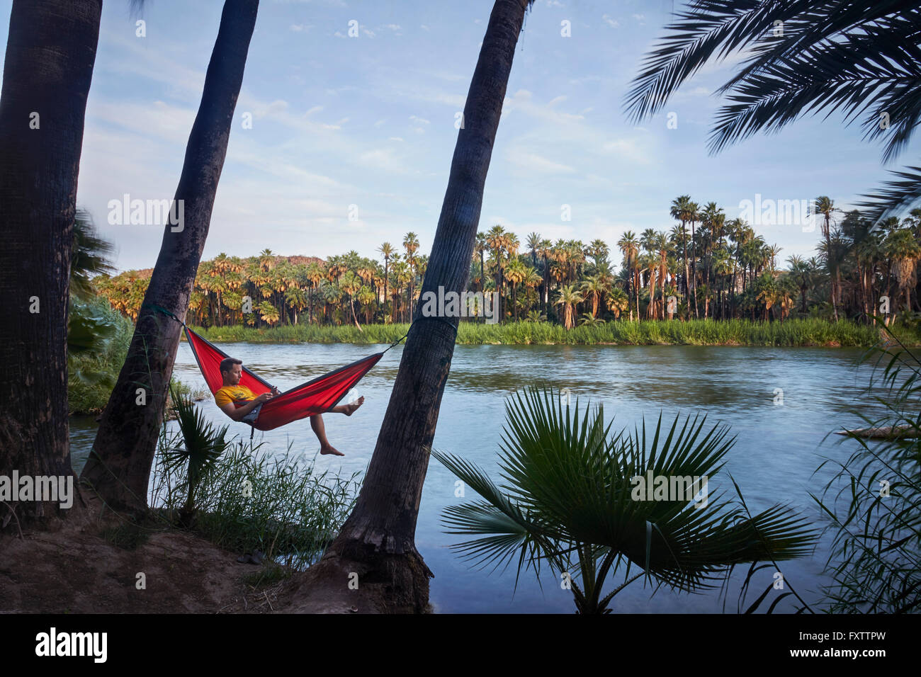 Man relaxing in hammock by lake, Baja California, Mexique Banque D'Images