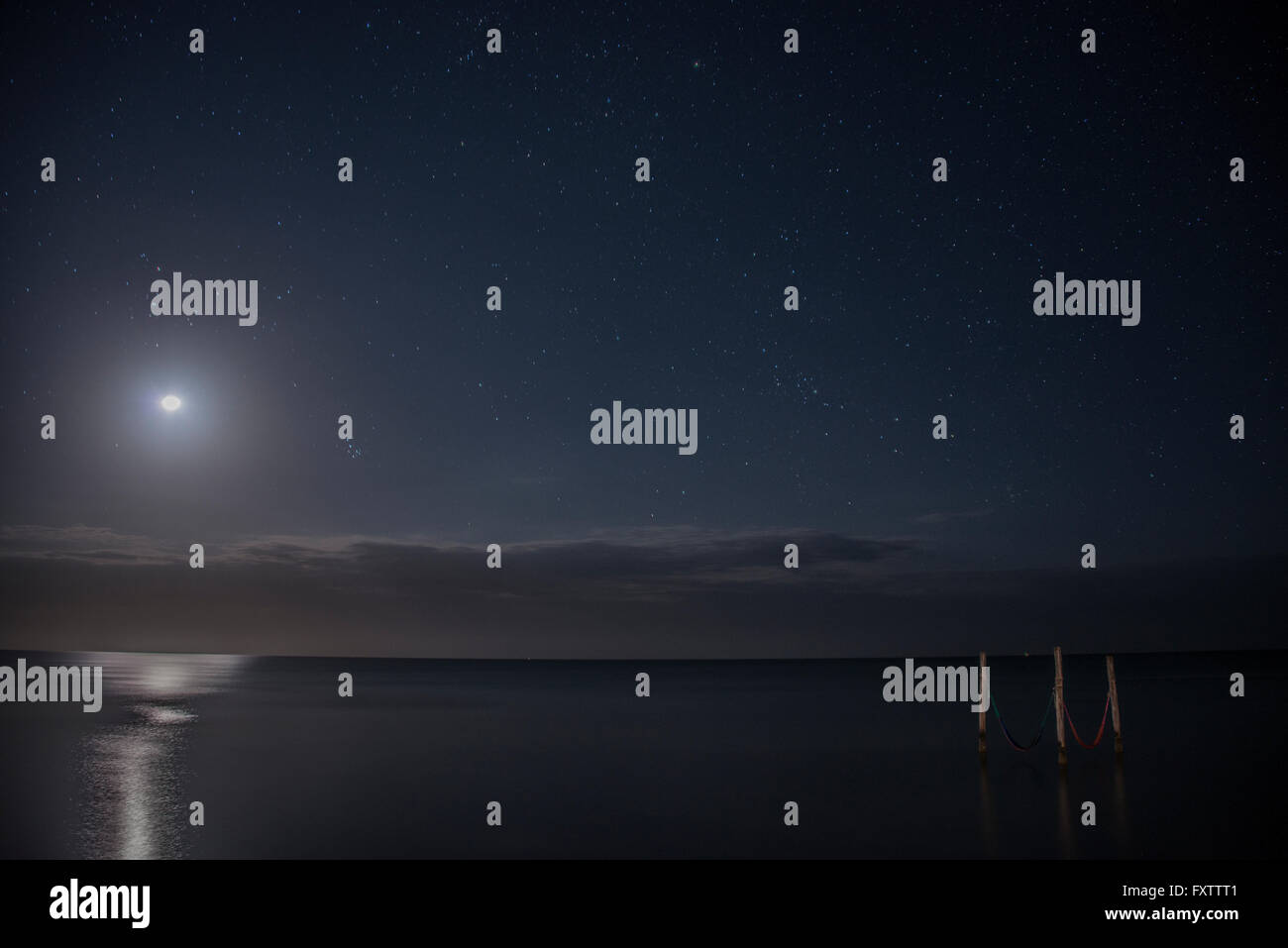 Ciel étoilé et la pleine lune éclairer hamacs emblématique sur les eaux, Isla Holbox, Mexique Banque D'Images