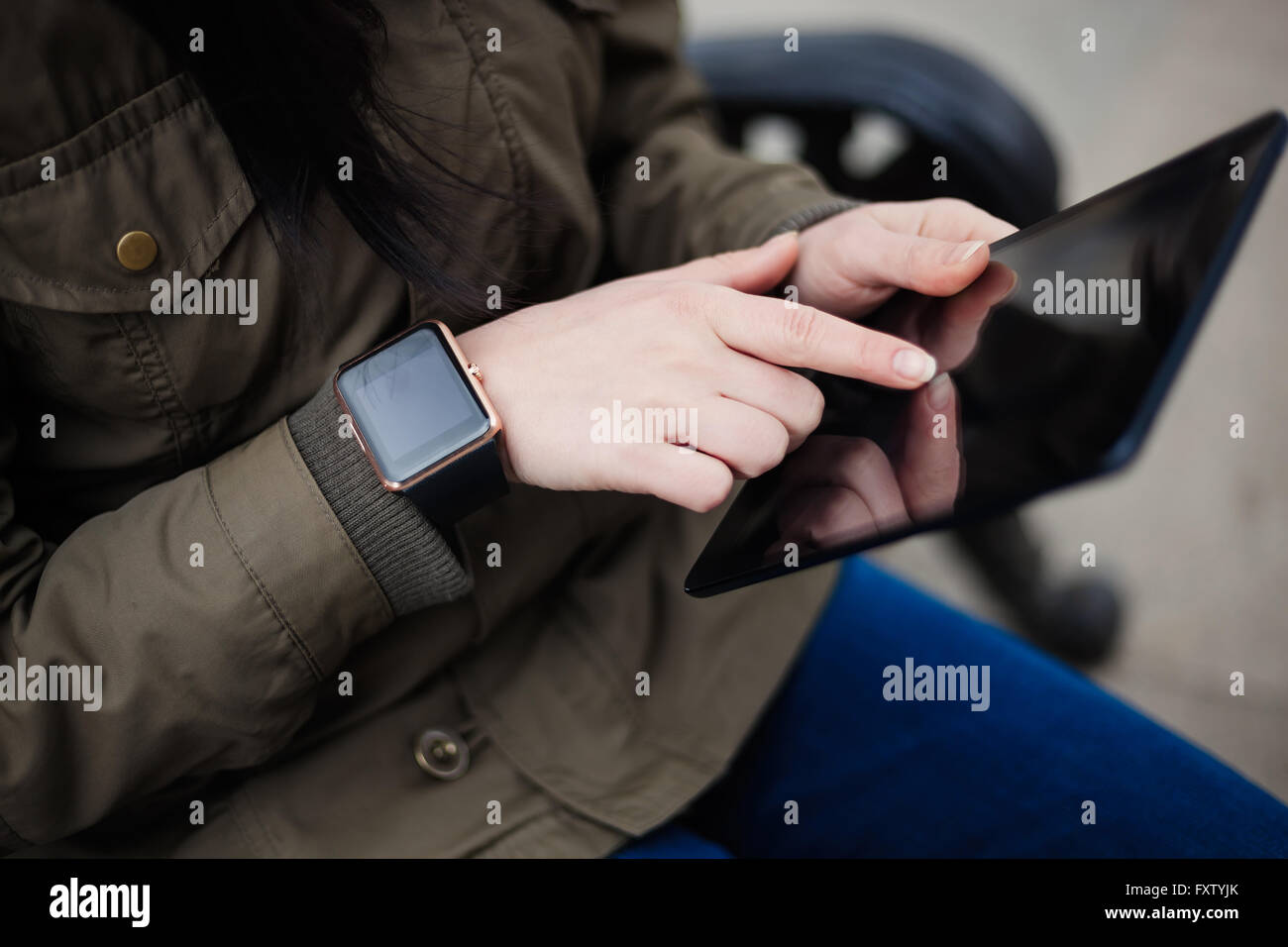 Hipster girl à parka coat using tablet pc avec smart watch sur sa main. Ce nouveau gadget vous permet de rester toujours connecté à internet et les réseaux sociaux à partir de n'importe où vous voulez. Banque D'Images