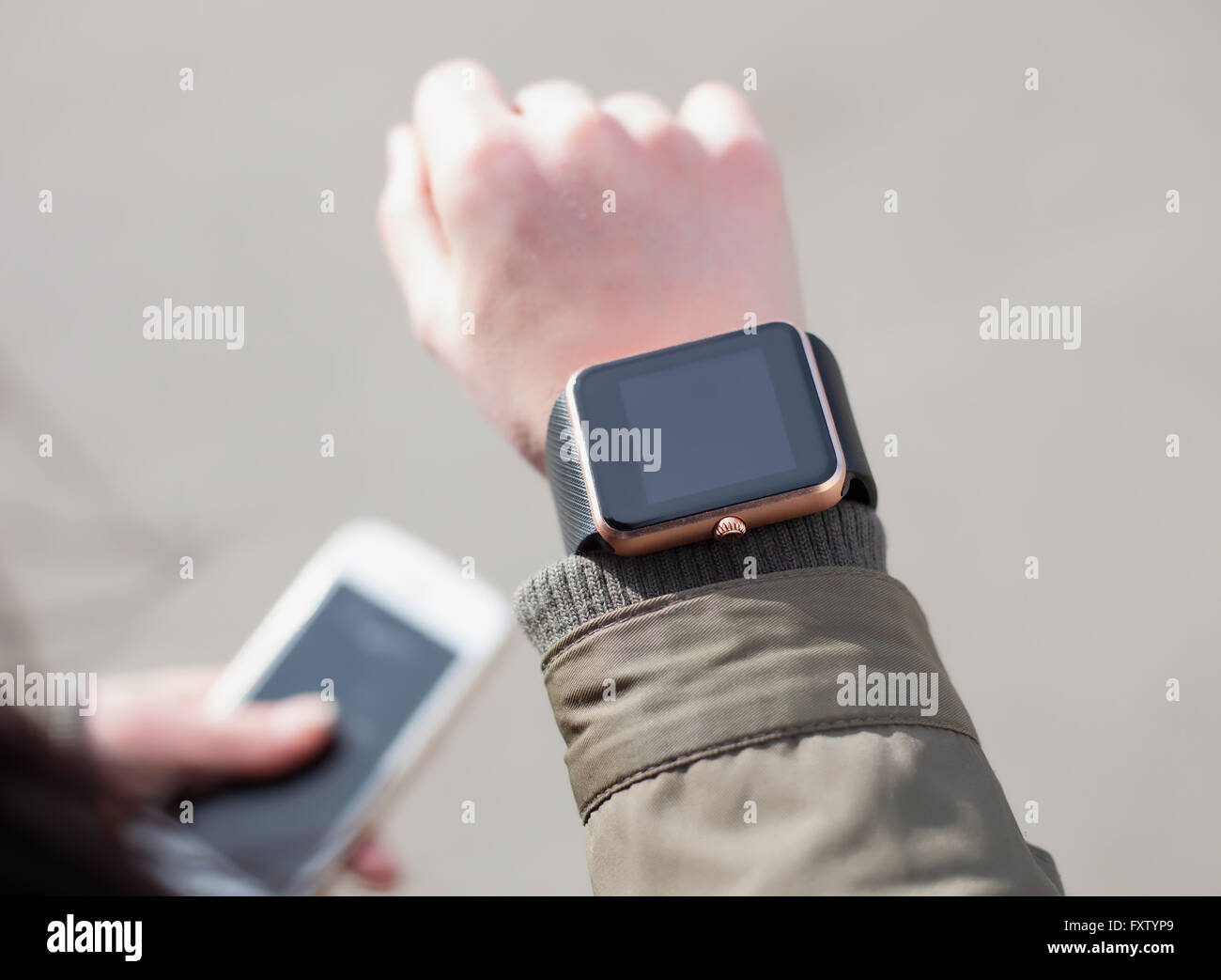 Femme regardant sa montre intelligente tout en maintenant un téléphone intelligent dans d'autres part. Ce nouveau gadget vous permettent de toujours rester connecté à internet et les réseaux sociaux à partir de n'importe où vous voulez. Banque D'Images