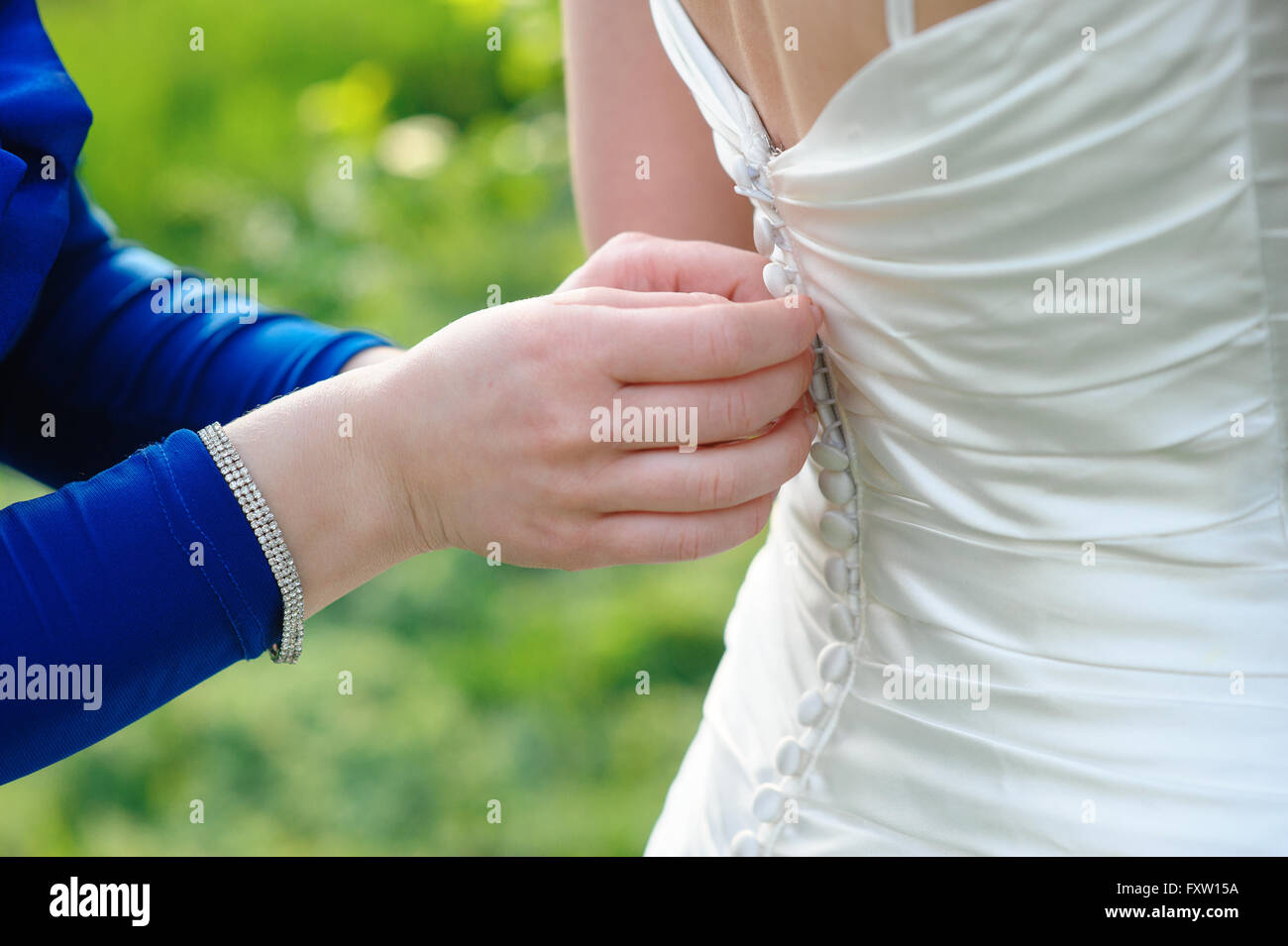 C'est demoiselle d'aider la mariée à s'habiller de jour weddihg Banque D'Images