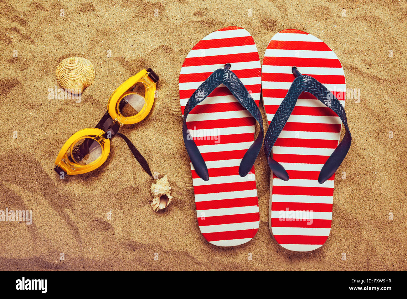 Paire de tongs ou des tongs et lunettes de natation sur la plage de sable, vue de dessus des vacances locations accessoires sur l'été de sable Banque D'Images