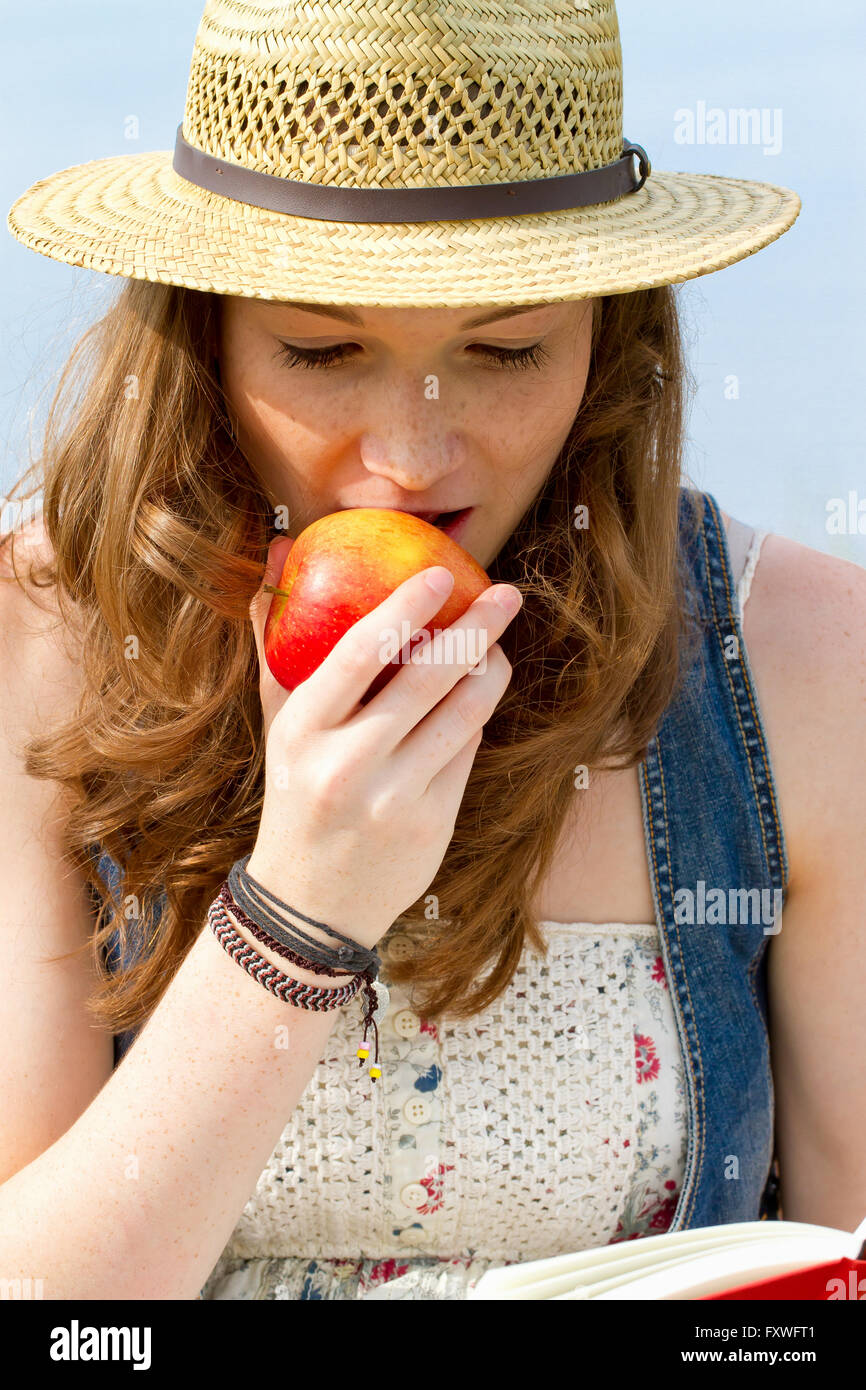 Jeune femme de manger une pomme et la lecture d'un livre Banque D'Images