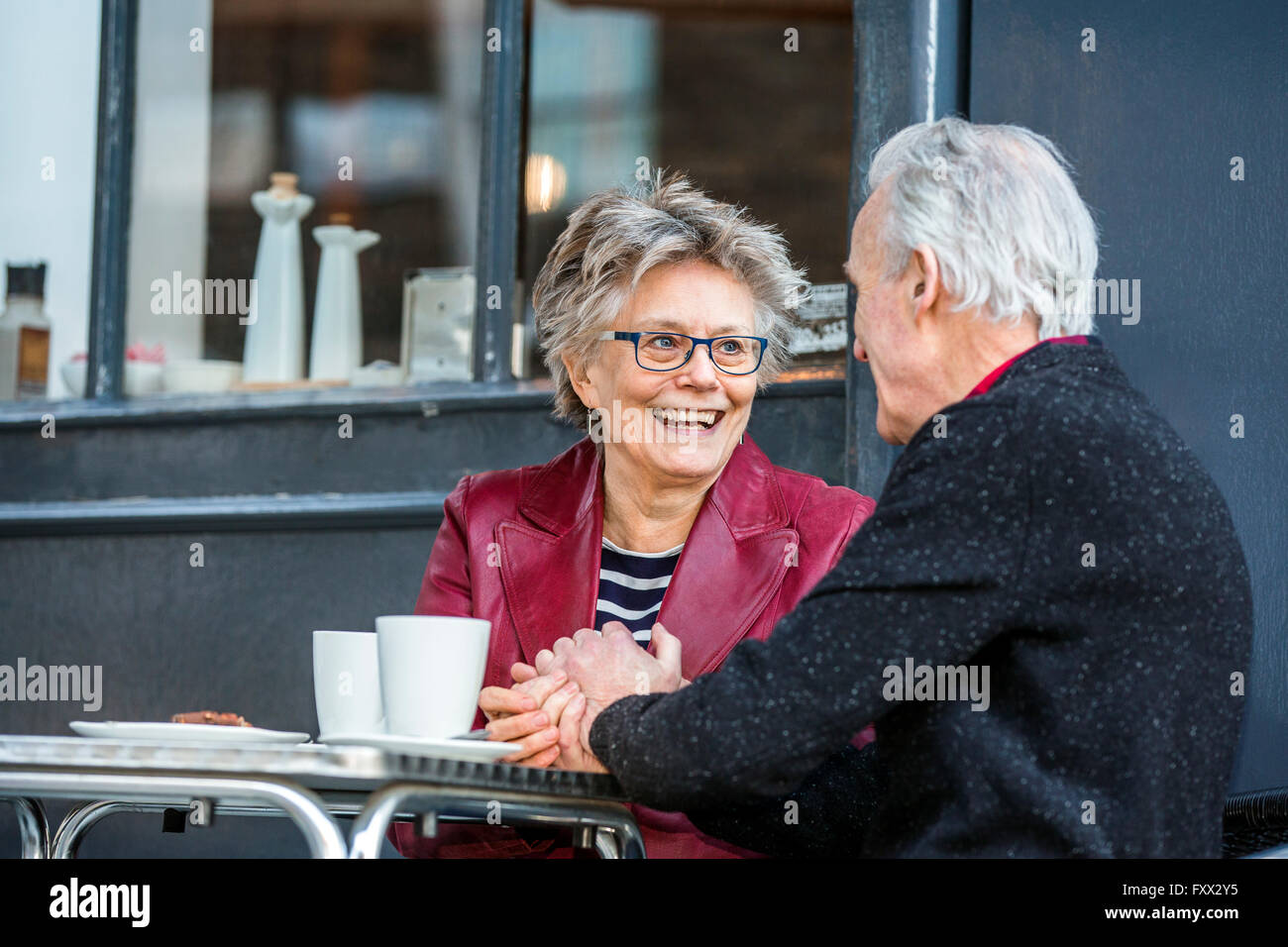 Romantic senior couple holding hands at sidewalk cafe Banque D'Images