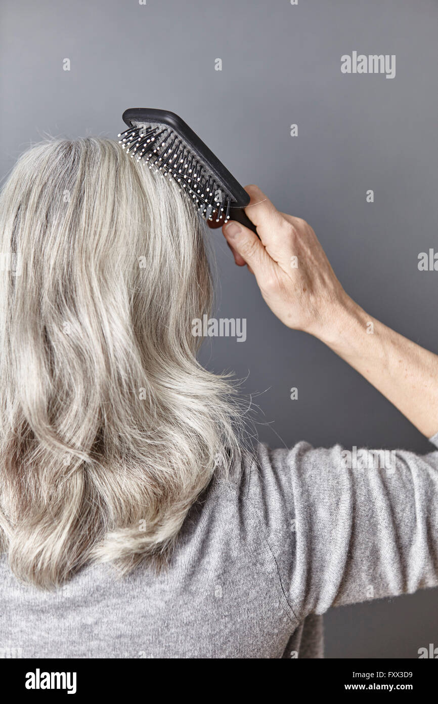 Vue arrière du brossage femme longs cheveux gris Banque D'Images
