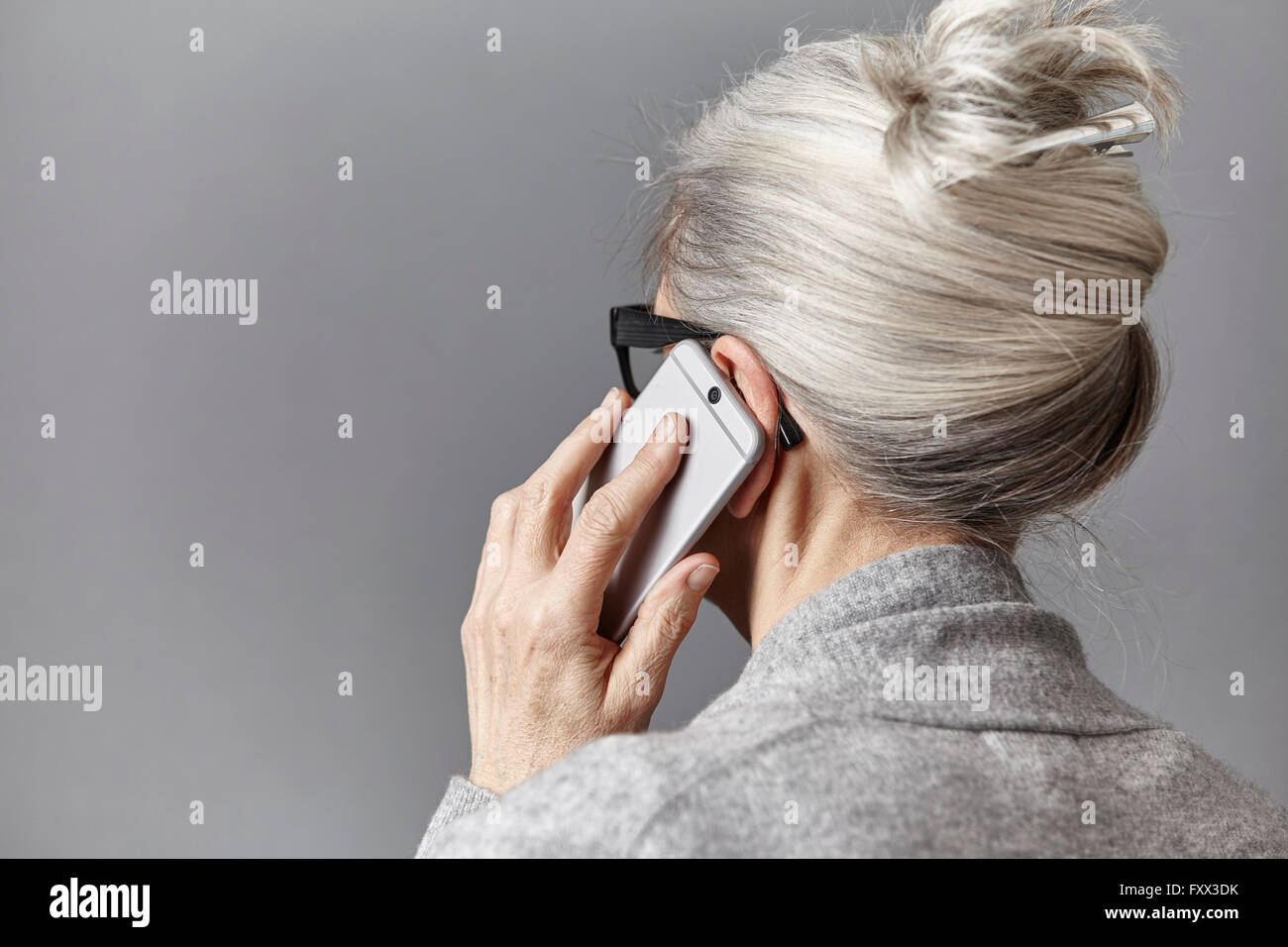 Grey haired woman using smartphone pour faire des appels téléphoniques Banque D'Images