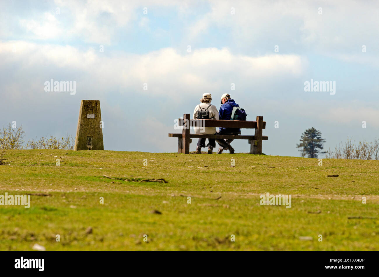 Vieux couple actif de marcheurs assis sur un banc près de trig point Banque D'Images