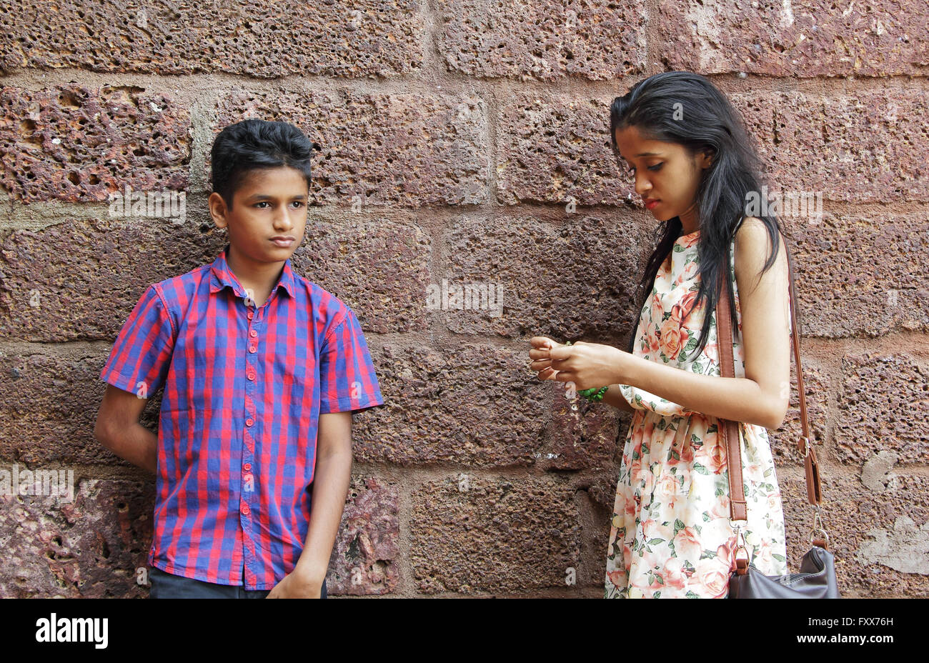 Teenage girl and boy dans l'humeur triste et en colère, debout contre un mur de briques en latérite Banque D'Images