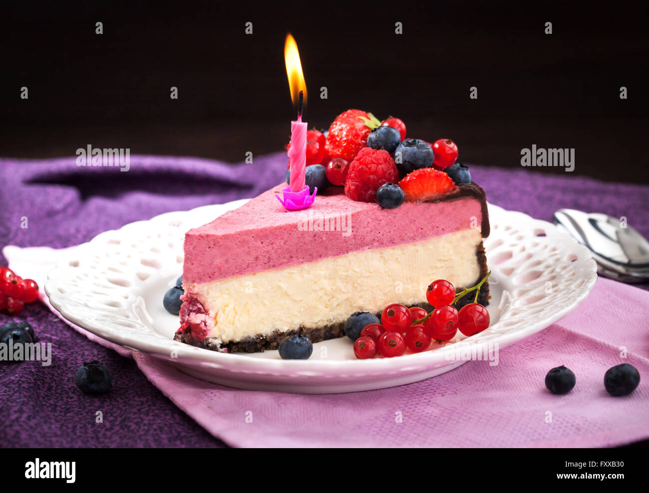 Partie de délicieux cheesecake framboise décorée avec des baies fraîches, chocolat et des bougies Banque D'Images