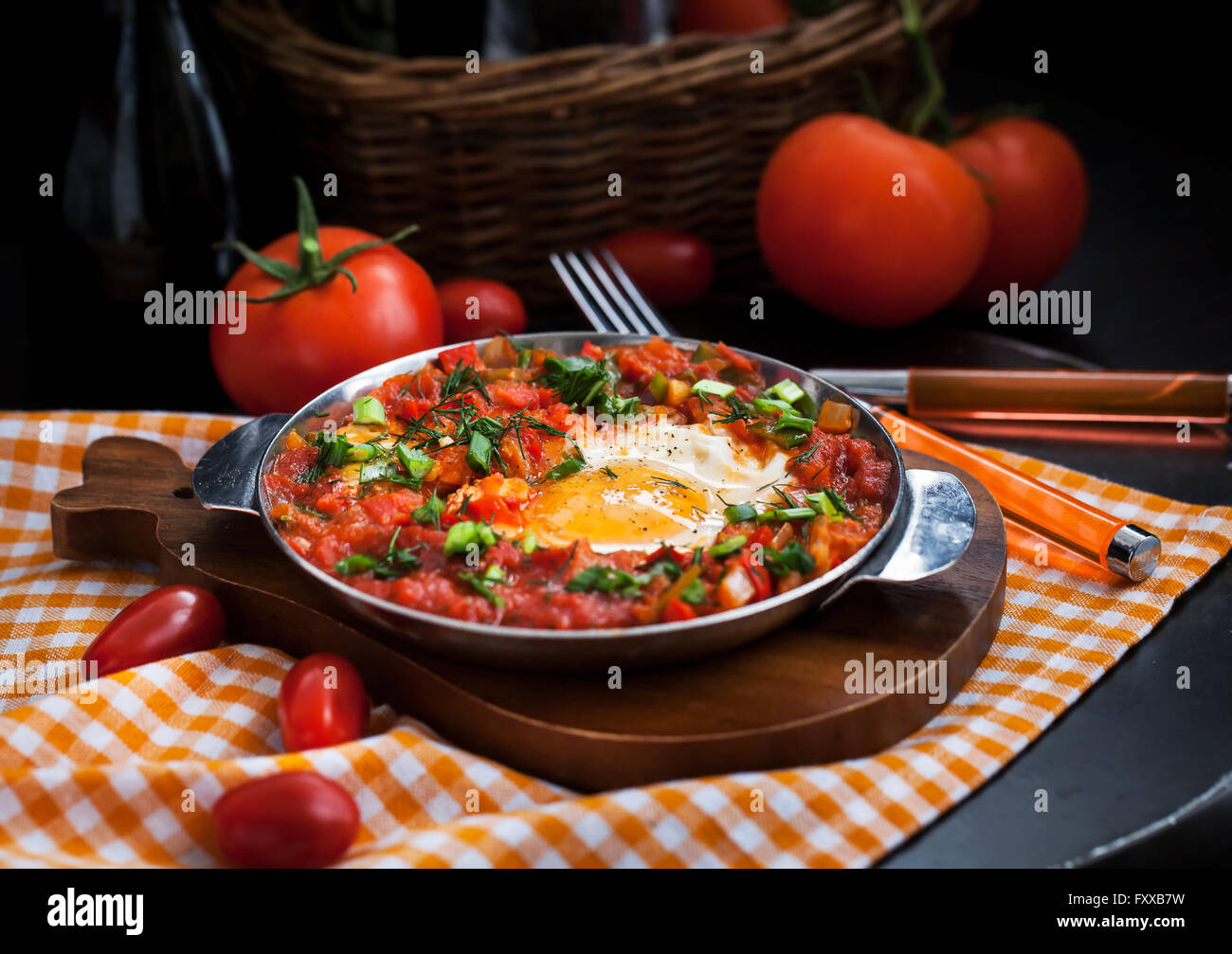 Shakshuka - oeufs au plat avec les tomates, l'oignon, le poivre et les épices dans poêle de fer, style sombre Banque D'Images