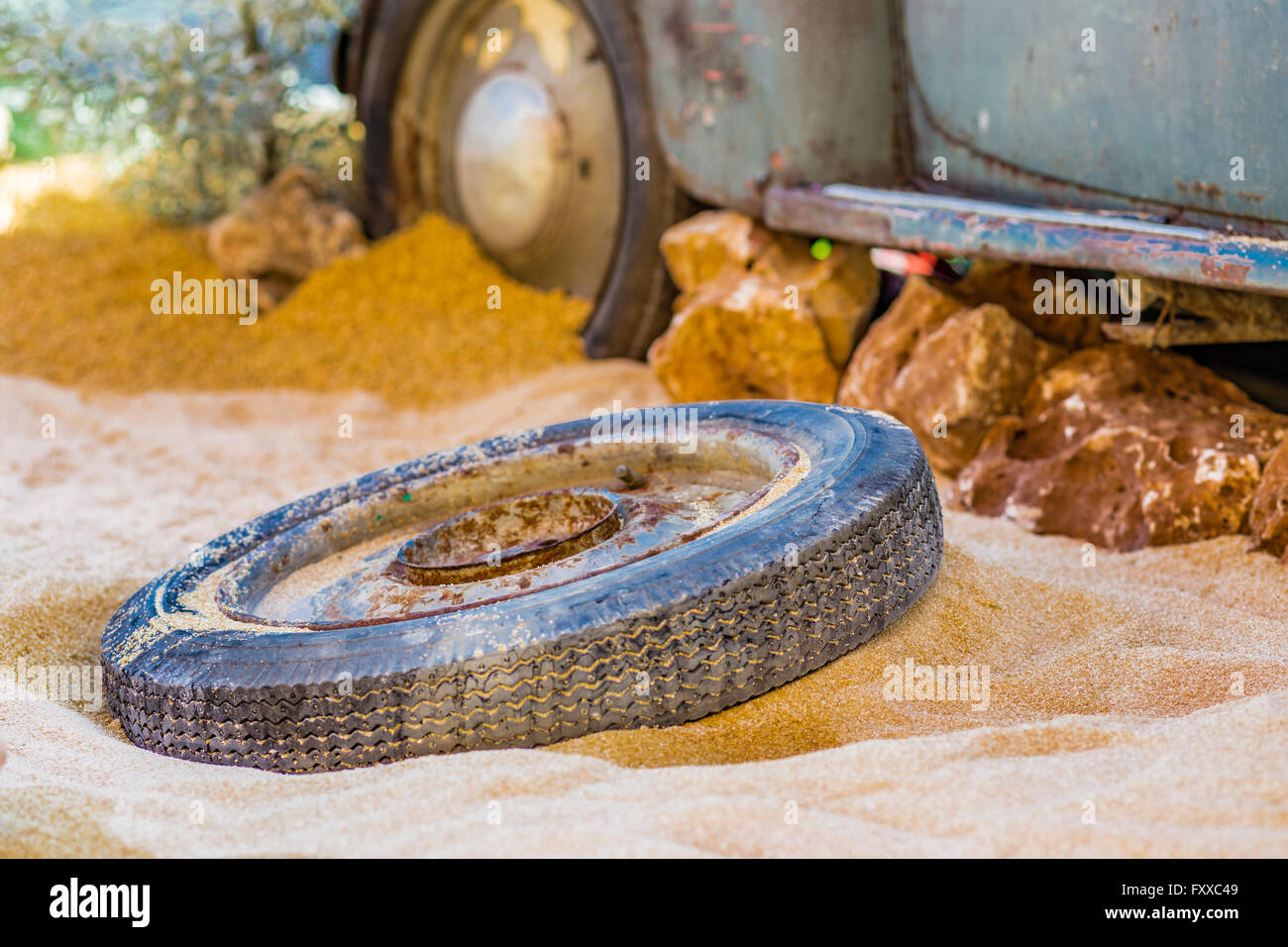 Carcasse d'une vieille voiture rouillée dans le désert de sable entourée de rochers et de cactus Banque D'Images