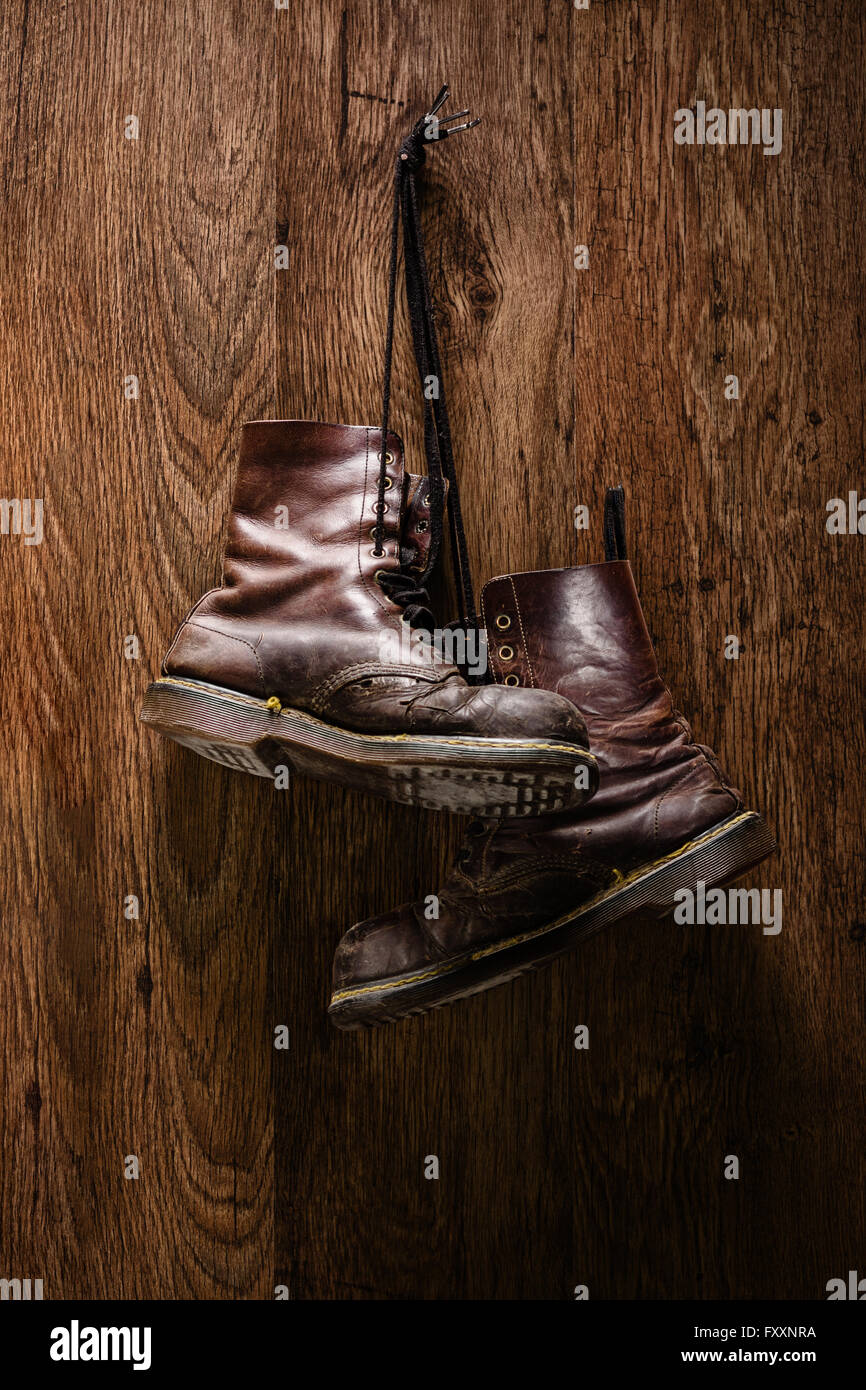 Shot verticale d'une vieille paire de bottes marron accroché sur un mur en bois Banque D'Images