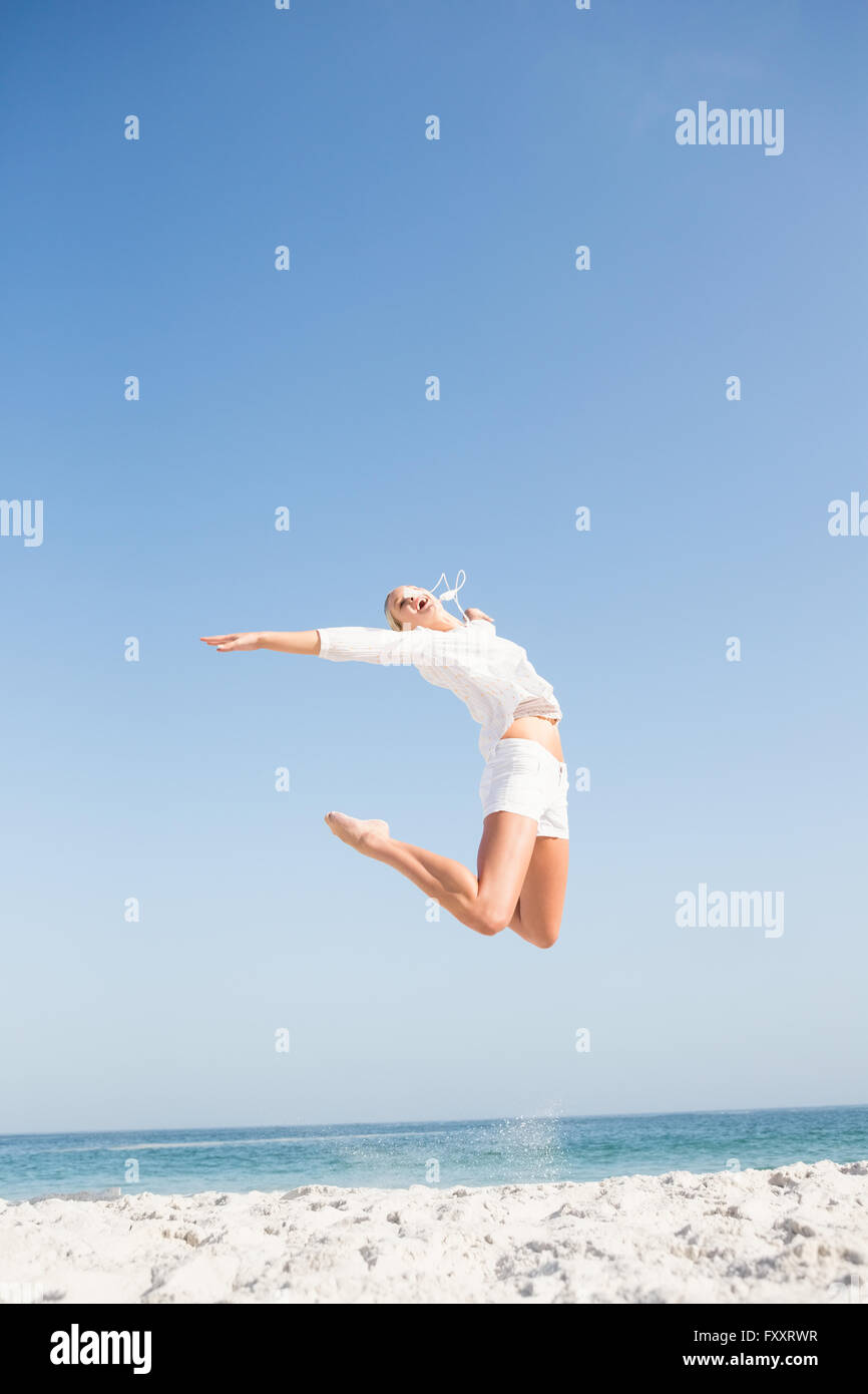 Blonde woman jumping on the beach Banque D'Images