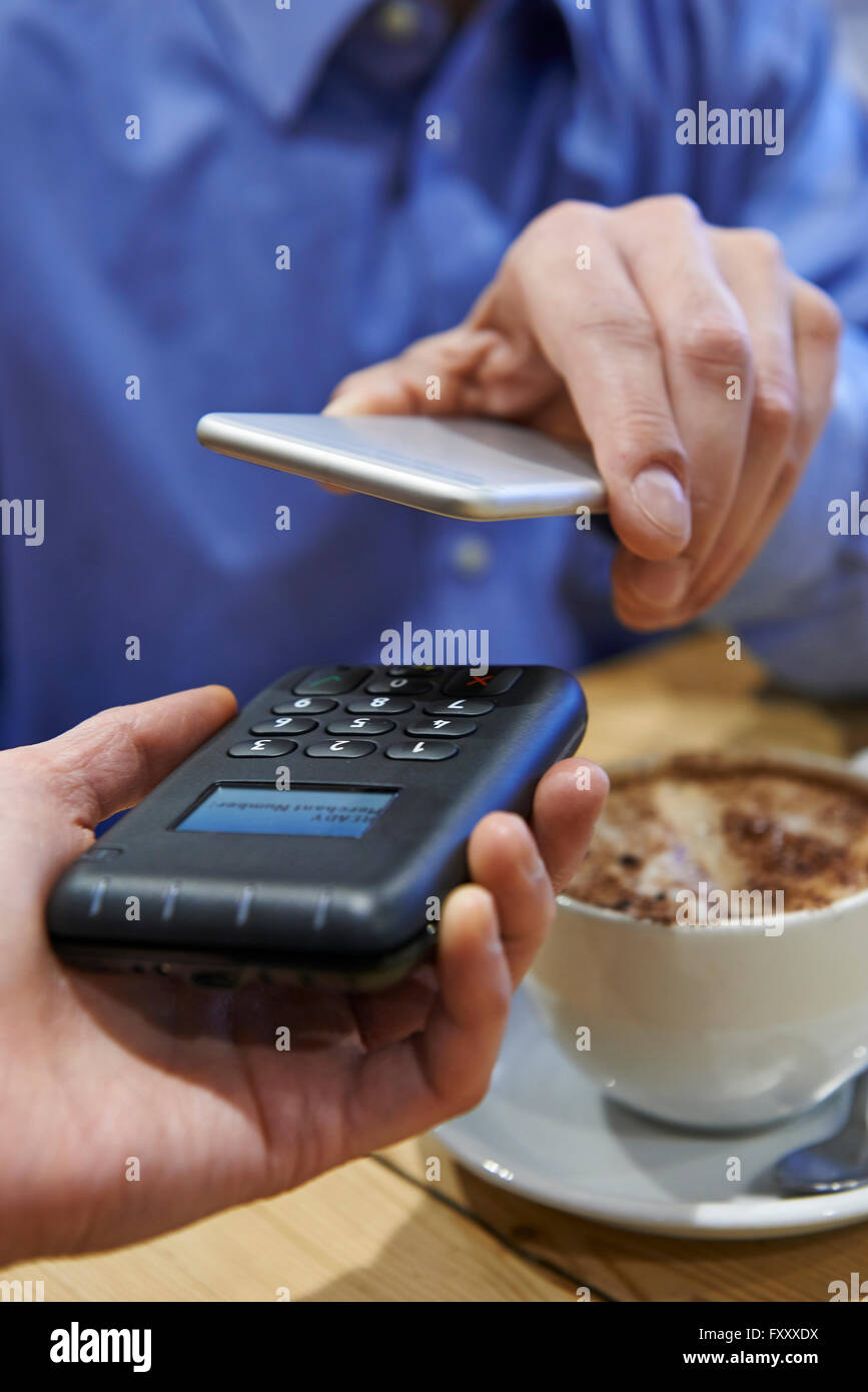 L'homme à l'aide de l'application de paiement sans contact sur téléphone mobile en Cafe Banque D'Images