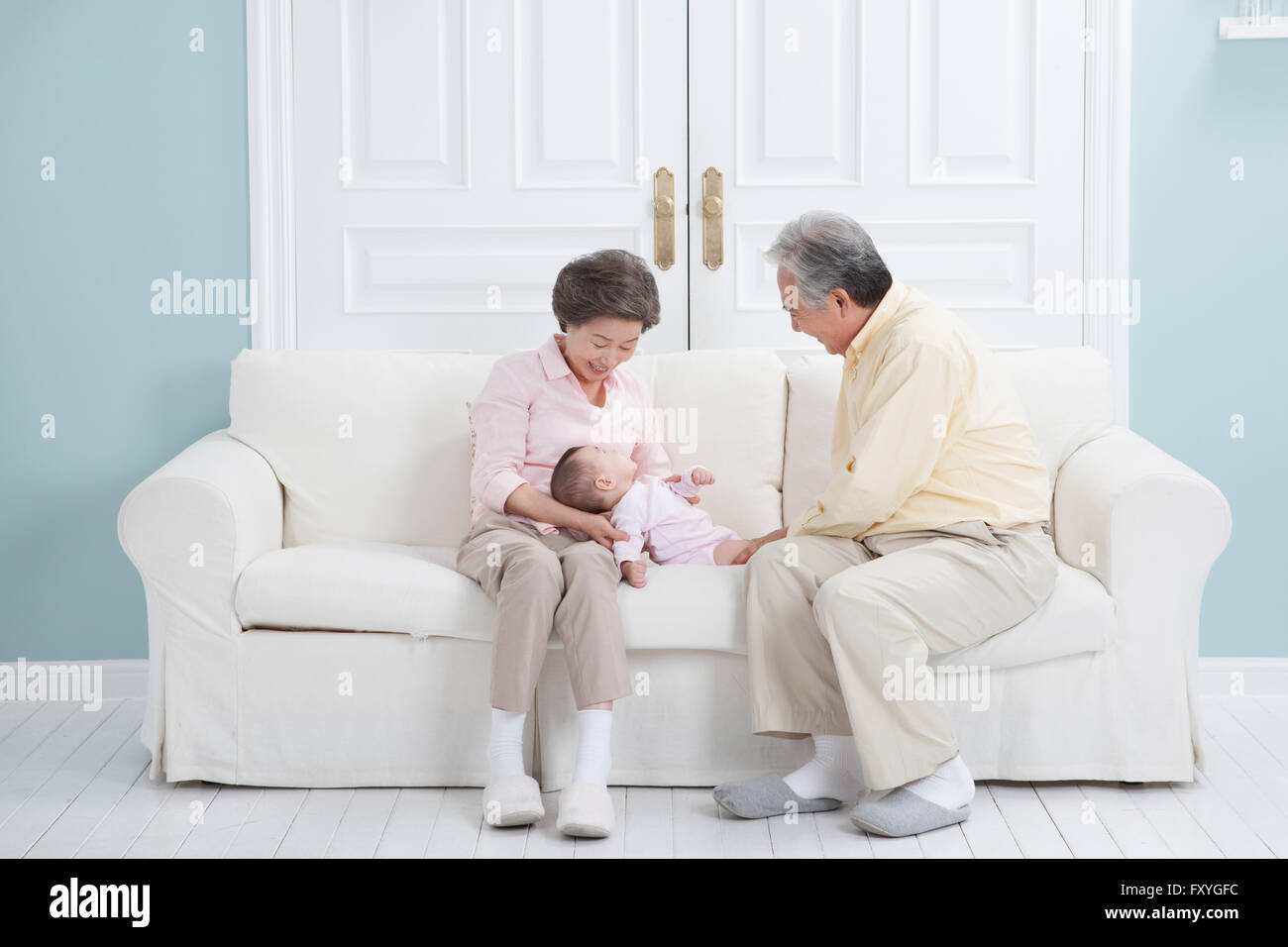 Couple assis sur un canapé en prenant soin du bébé couché sur la table Banque D'Images