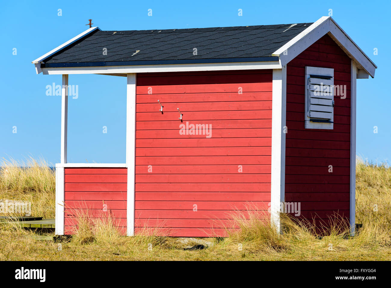 La Suède, Falsterbo - Avril 11, 2016 : rouge, blanc et noir ou en bois cabane de plage le long de la cabine de bain rivage sablonneux. De l'herbe sèche Banque D'Images