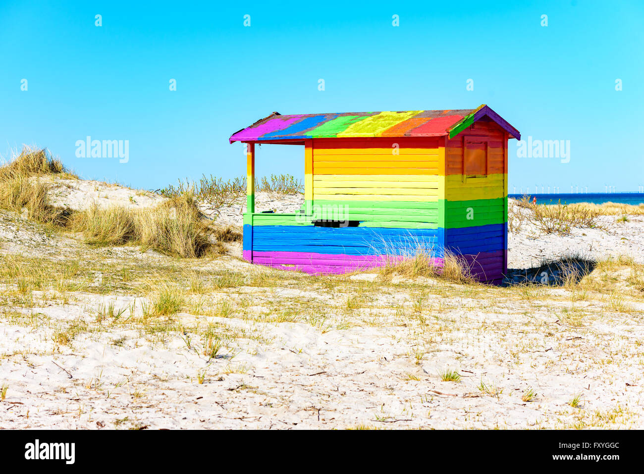 La Suède, Falsterbo - Avril 11, 2016 : en bois peint Rainbow Beach Hut ou cabine de baignade le long du rivage sablonneux. L'herbe sèche et s Banque D'Images