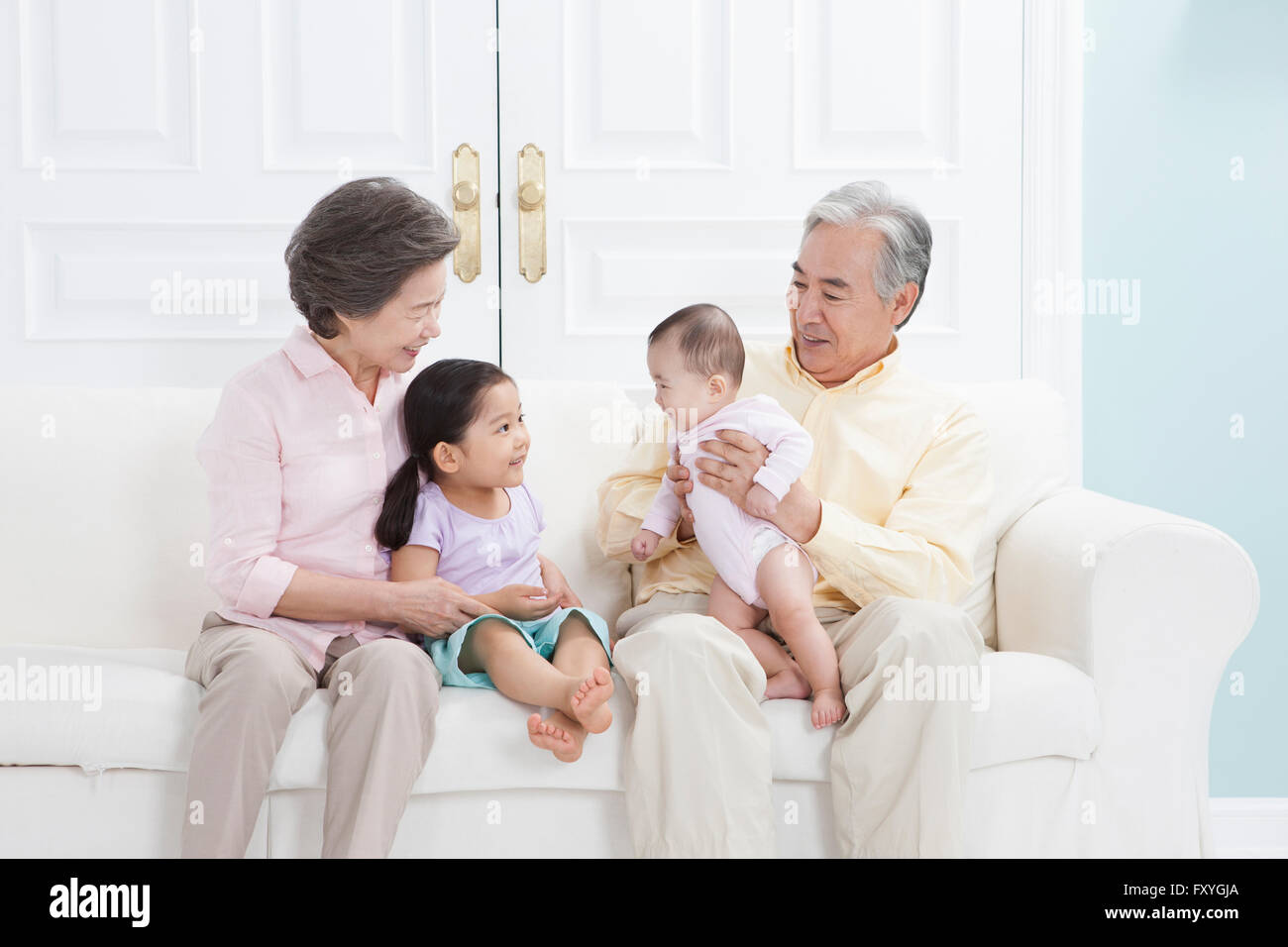 Les grands-parents d'être heureux avec leurs petits-enfants, tous assis sur un canapé et souriant Banque D'Images