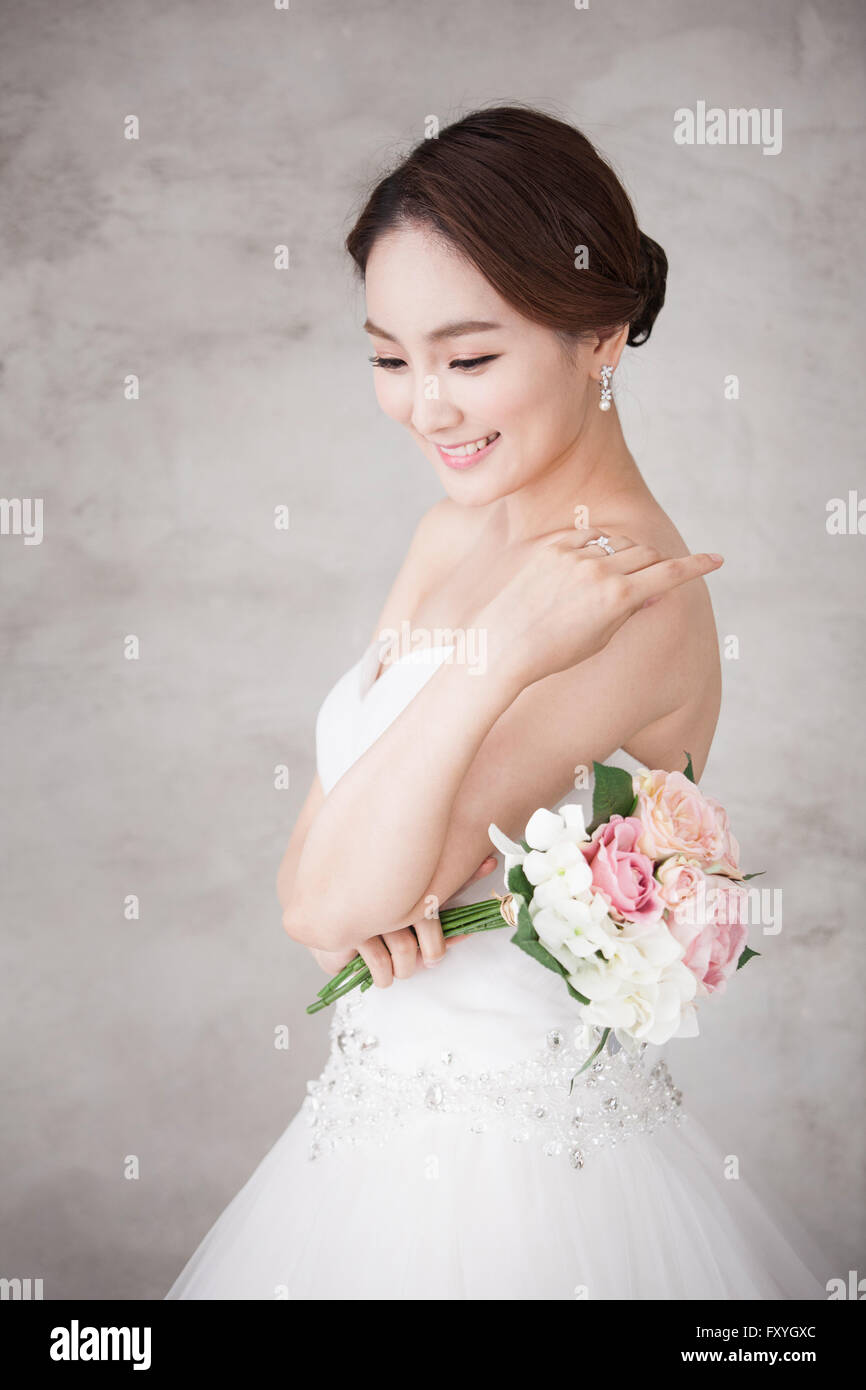 Bride holding a bouquet et regardant vers le bas avec sa main près de son épaule Banque D'Images