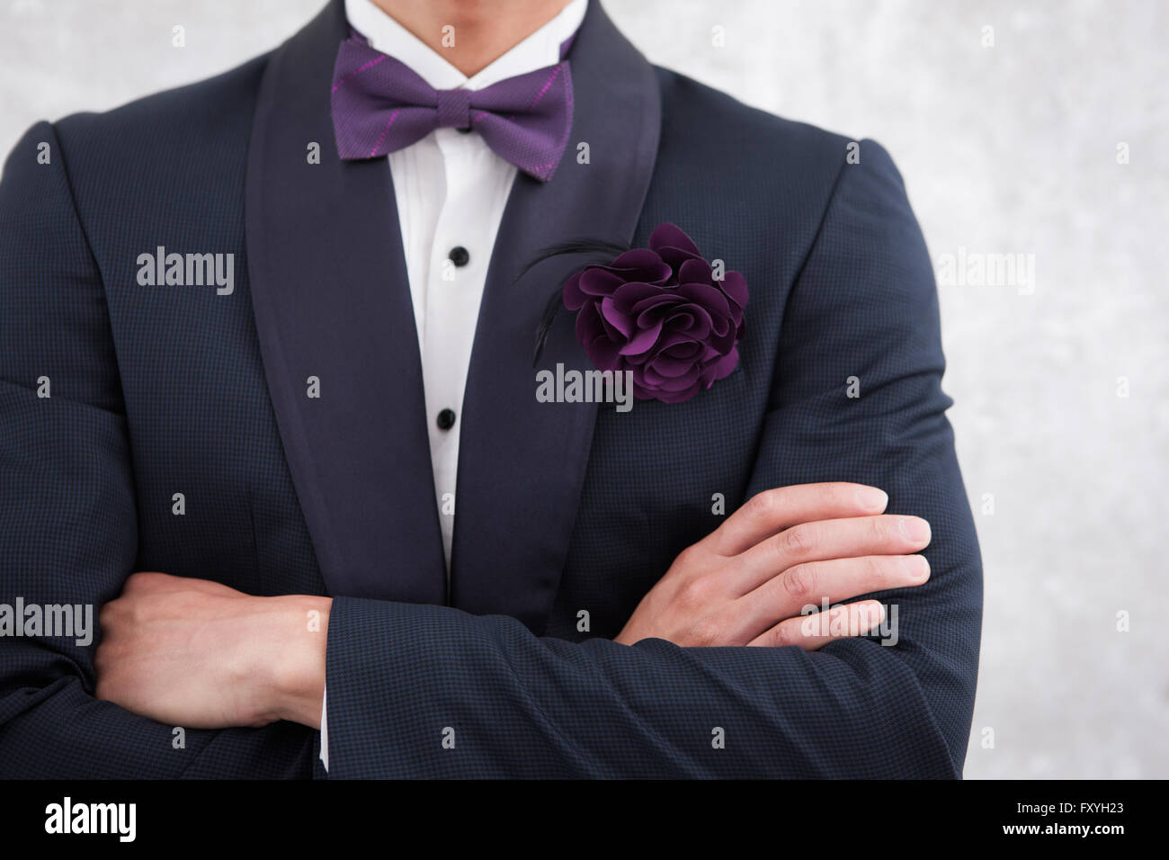 Man in tuxedo avec un corsage et dentelle avec ses bras croisés Banque D'Images