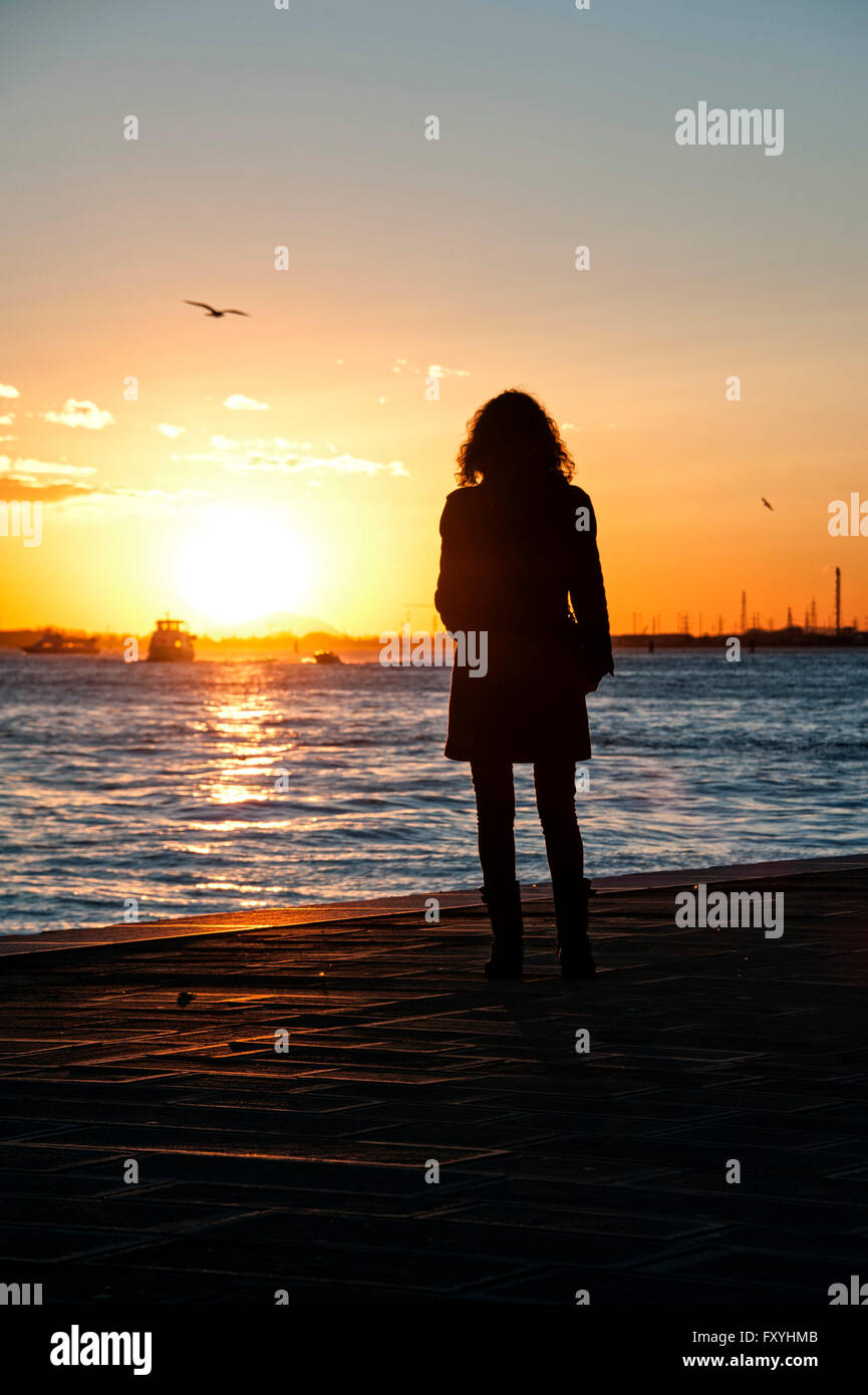 Femme regardant le coucher du soleil sur la promenade des Zattere, Venise, Italie Banque D'Images