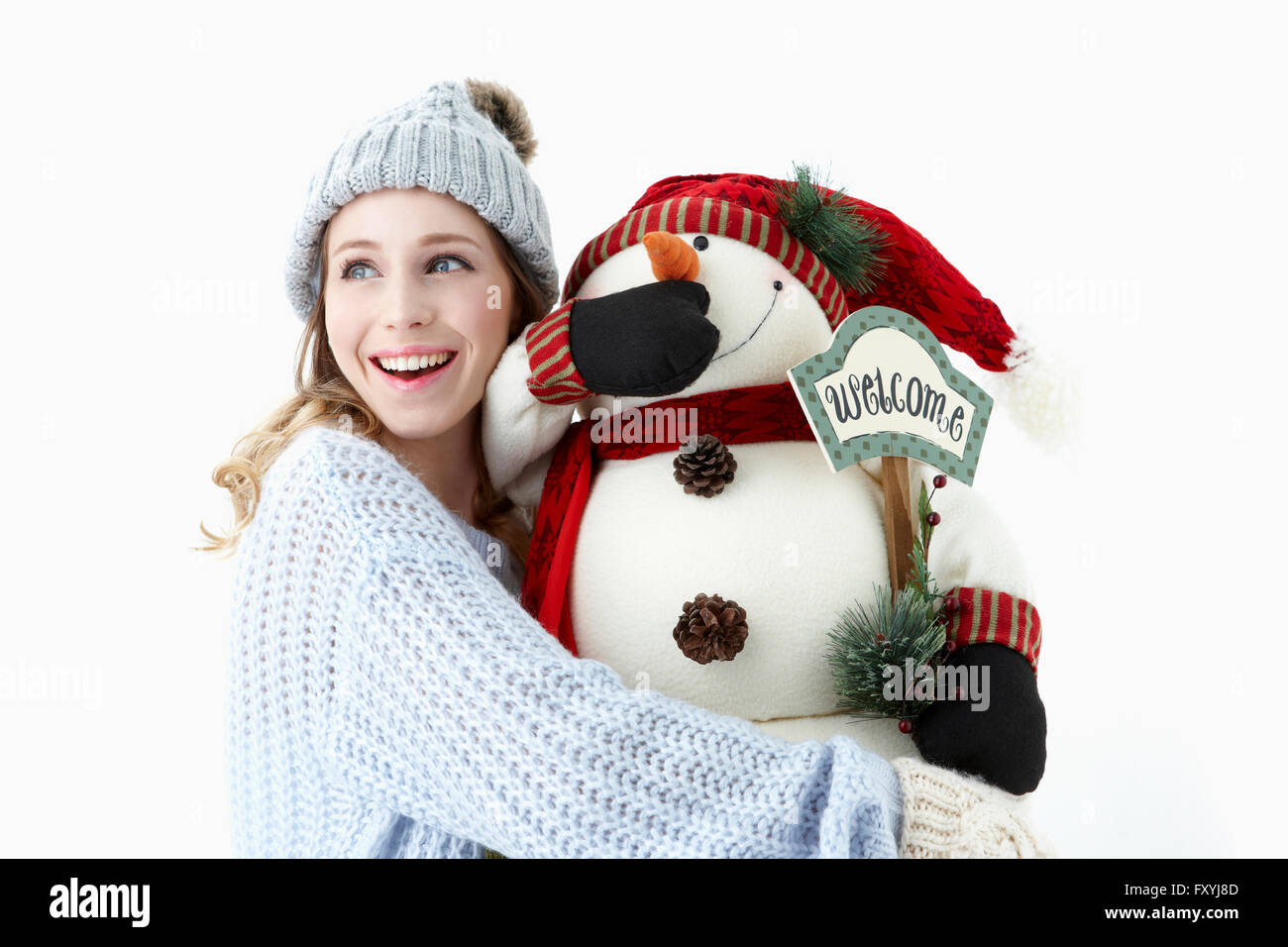 Woman in winter clothes holding snowman doll avec un sourire Banque D'Images