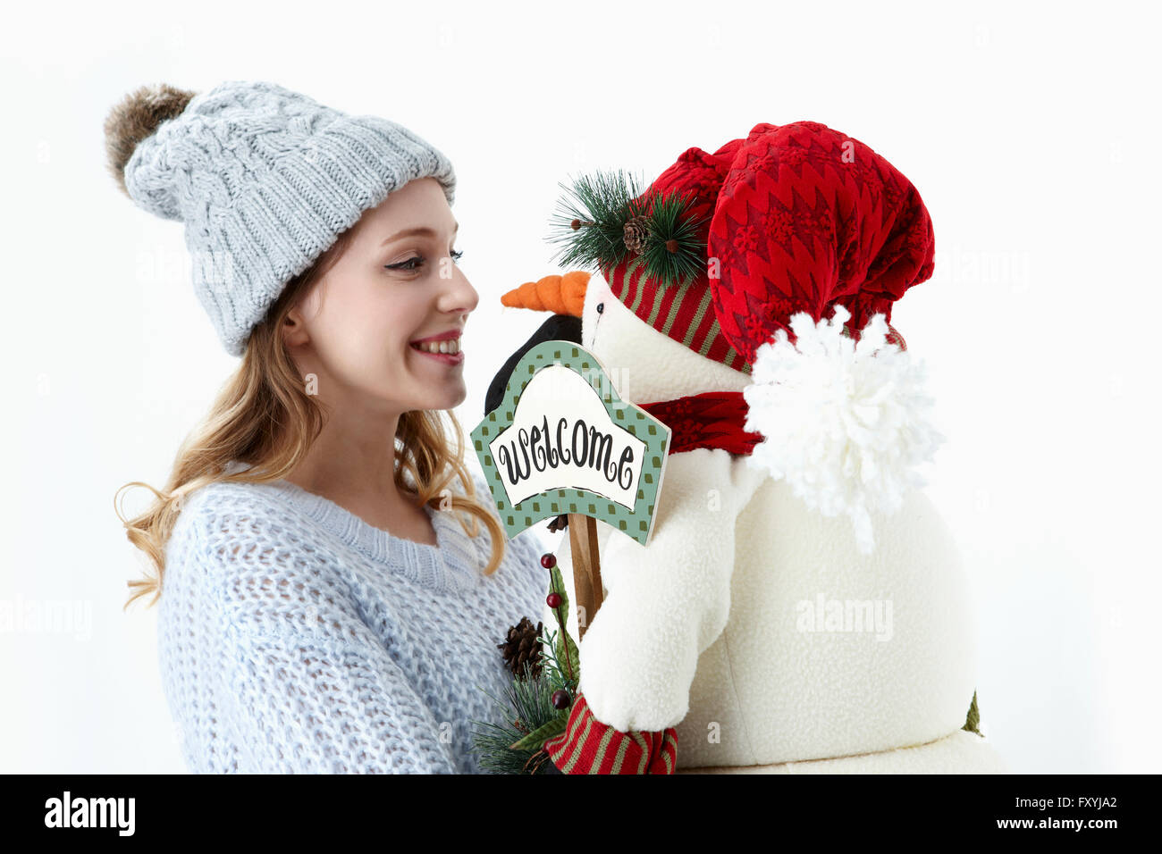 Woman in winter clothes holding snowman doll et à le regarder avec un sourire Banque D'Images