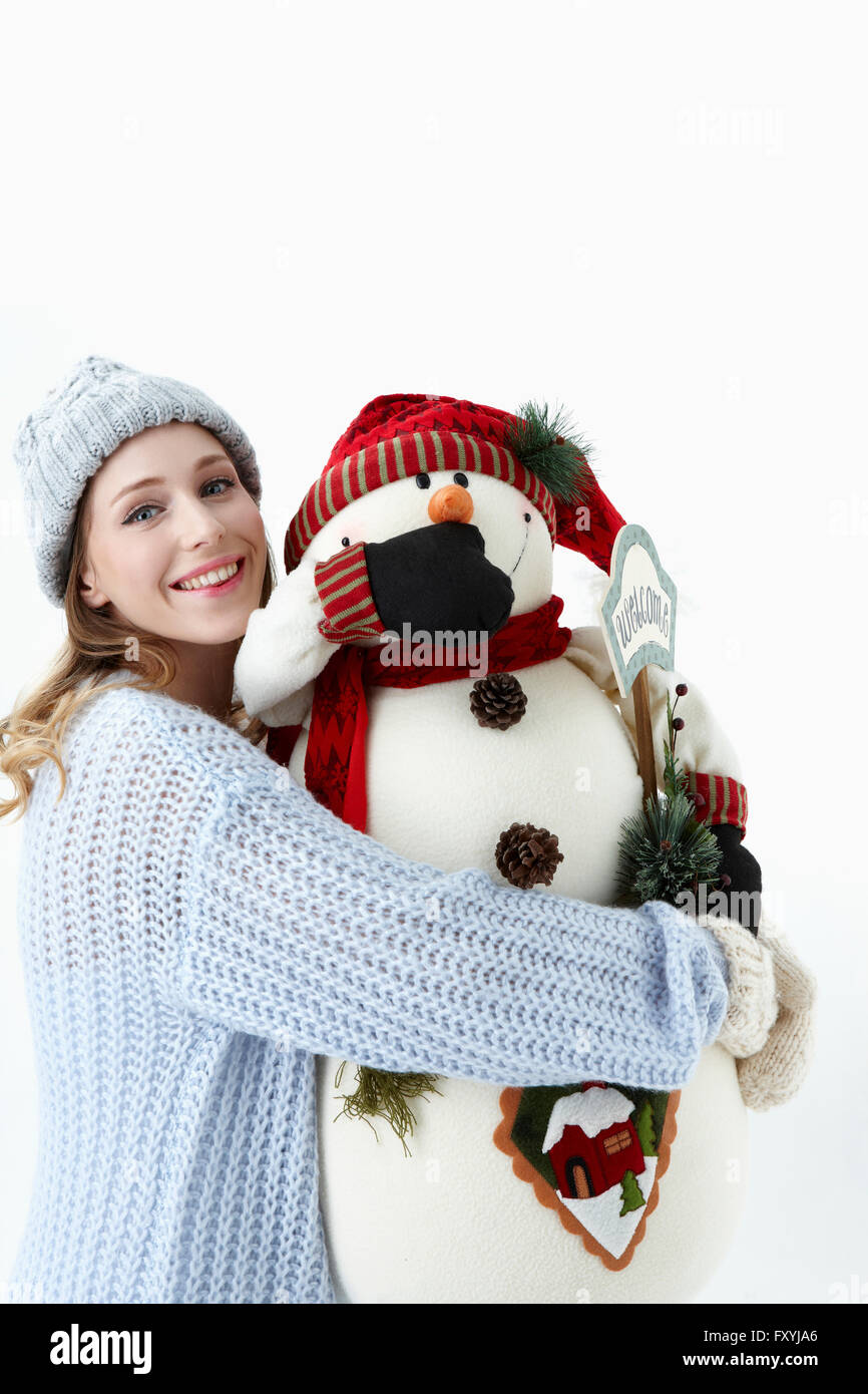 Woman in winter clothes holding snowman doll avec un sourire Banque D'Images