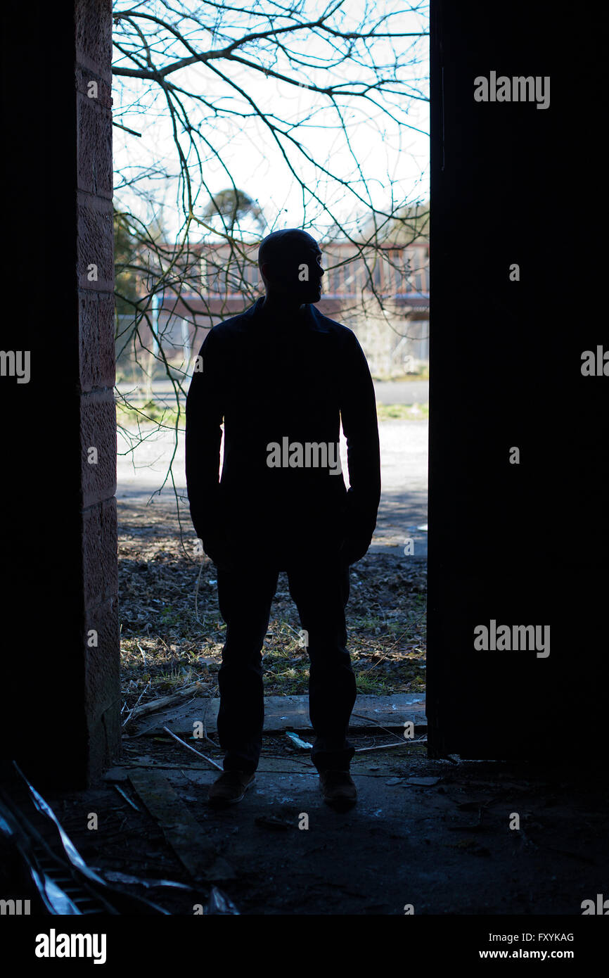Silhouette d'un homme aux portes d'un bâtiment abandonné Banque D'Images