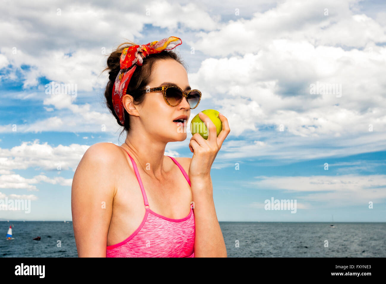 Jolie femme pinup dans lunettes manger green apple Banque D'Images