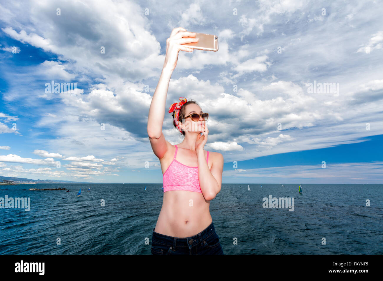 Jolie femme pinup lunettes à faire sur une plage avec le smartphone selfies Banque D'Images