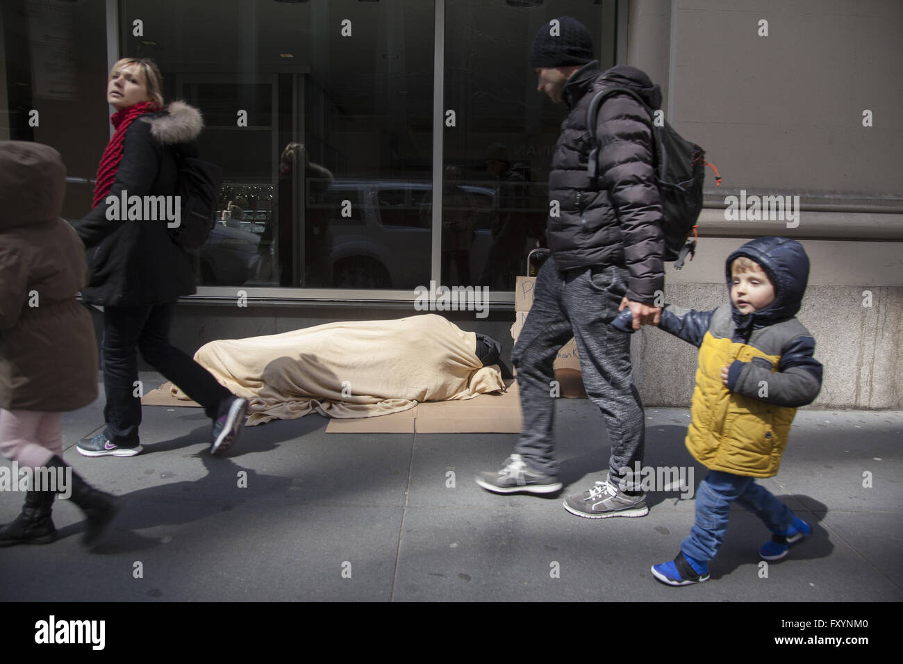 Personne sans-abri dort sur le trottoir à Midtown Manhattan, les gens passer. Banque D'Images
