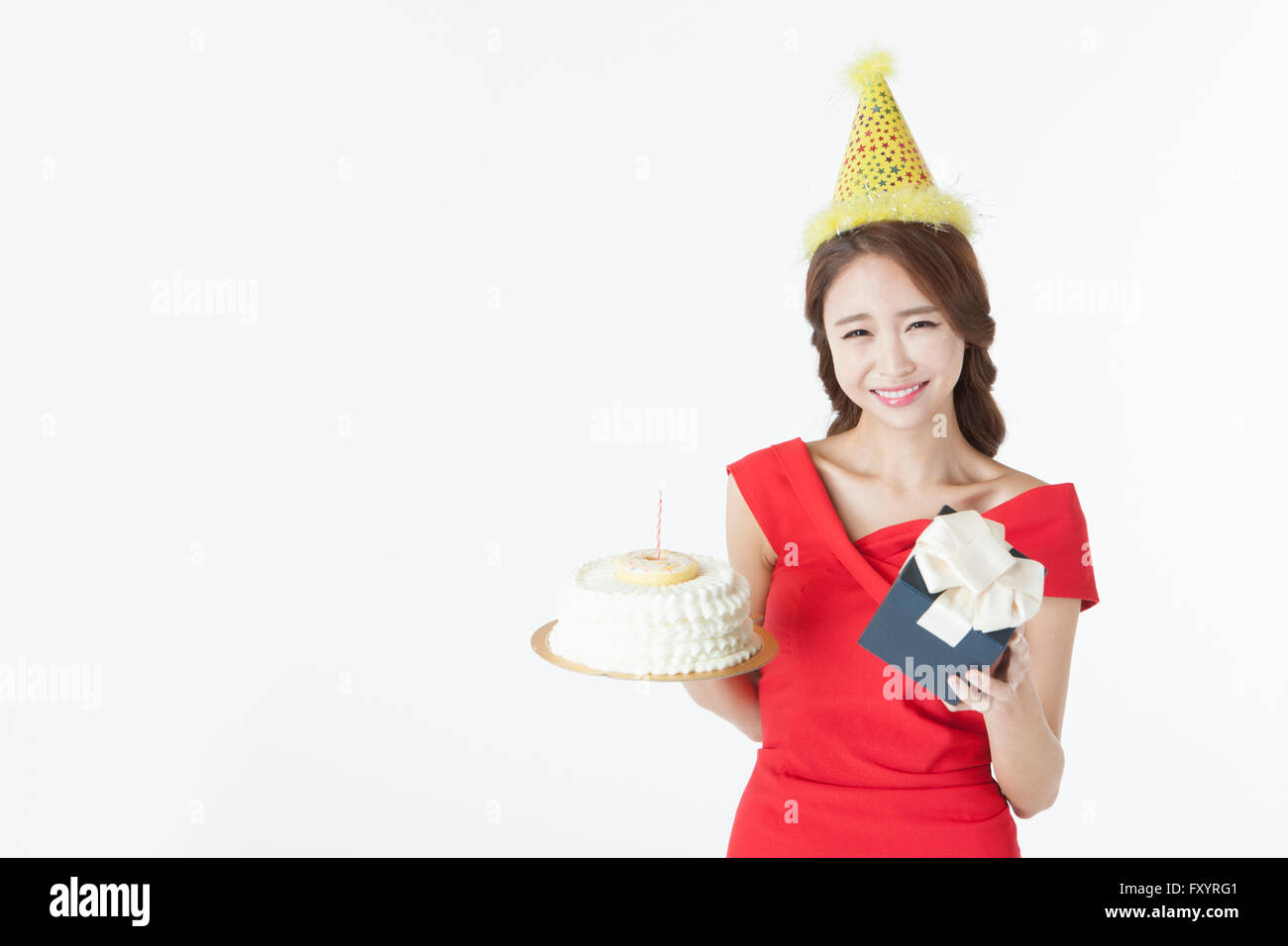 Portrait of young smiling woman holding un gâteau et un cadeau fort fixant à l'avant Banque D'Images