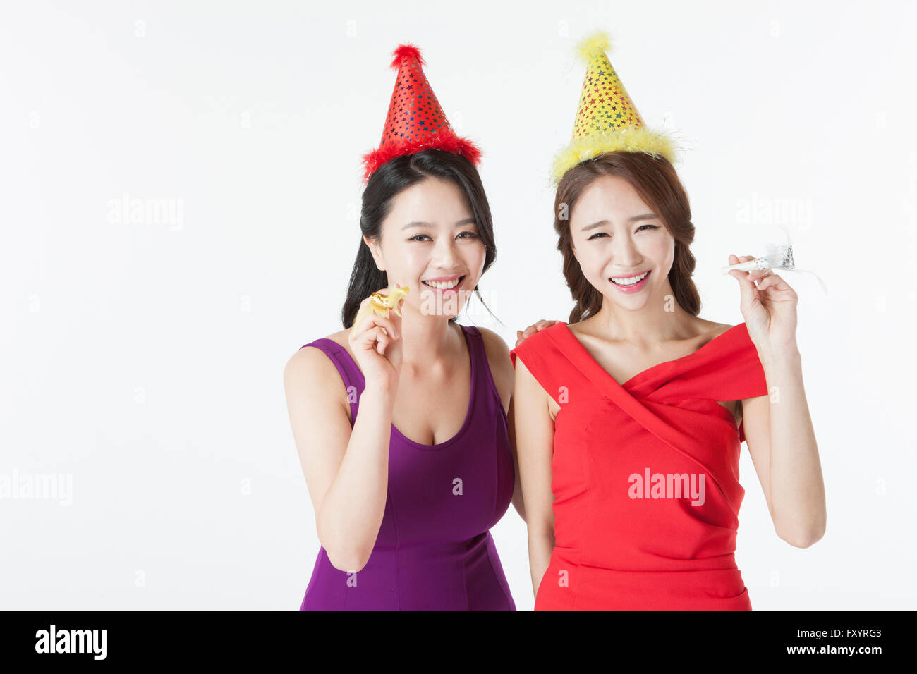 Portrait of smiling women holding party horns at party Banque D'Images