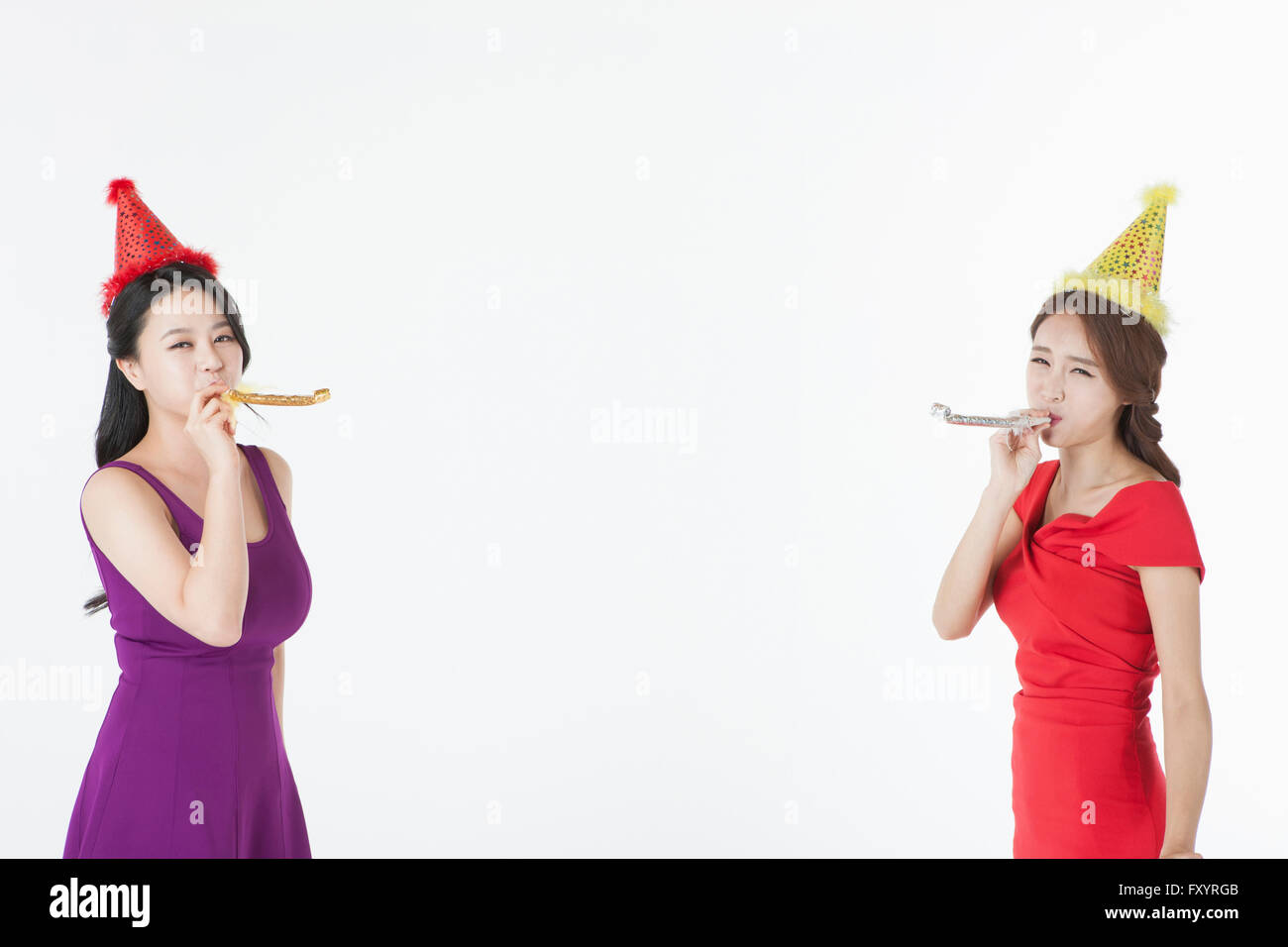 Side view portrait of smiling women blowing party horns Banque D'Images