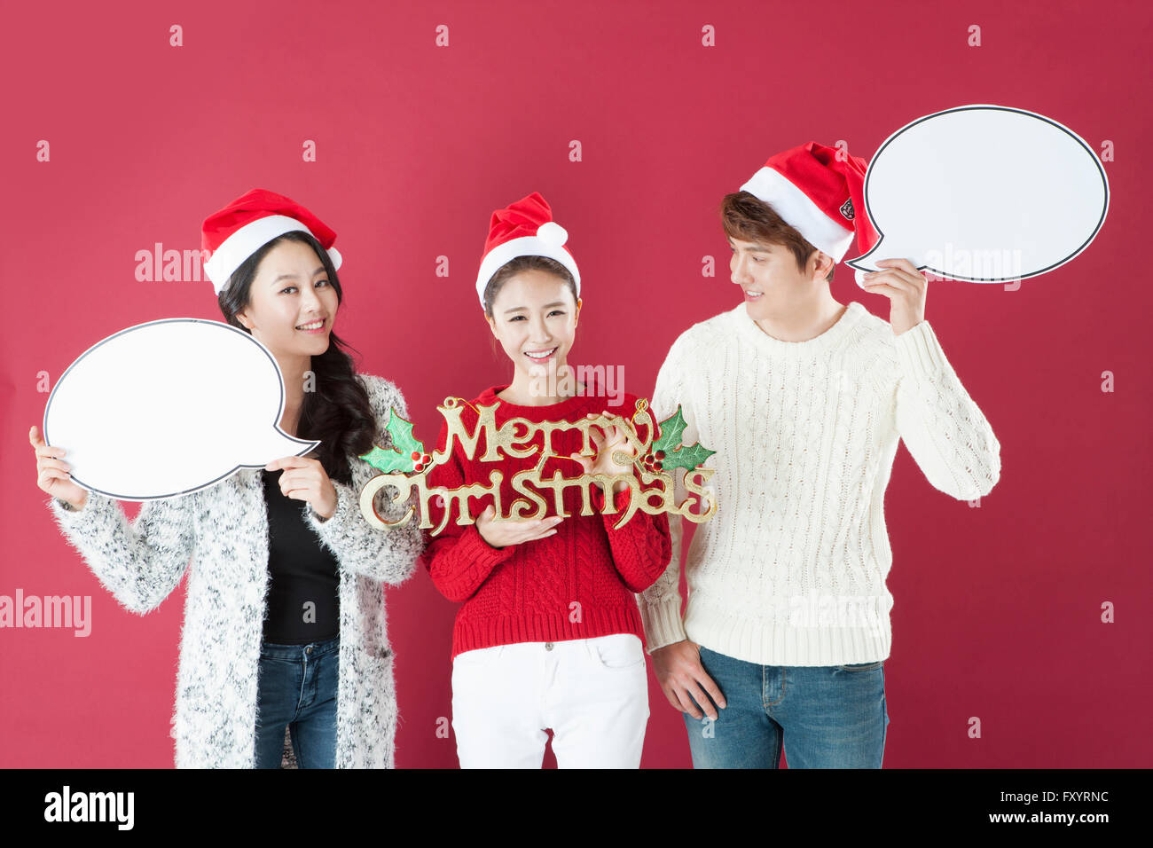 Portrait de trois jeunes gens souriants avec message de Joyeux Noël et phylactère Banque D'Images