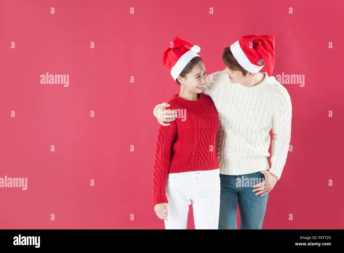 Jeune couple wearing santa hats in hans plaçant sur les épaules Banque D'Images