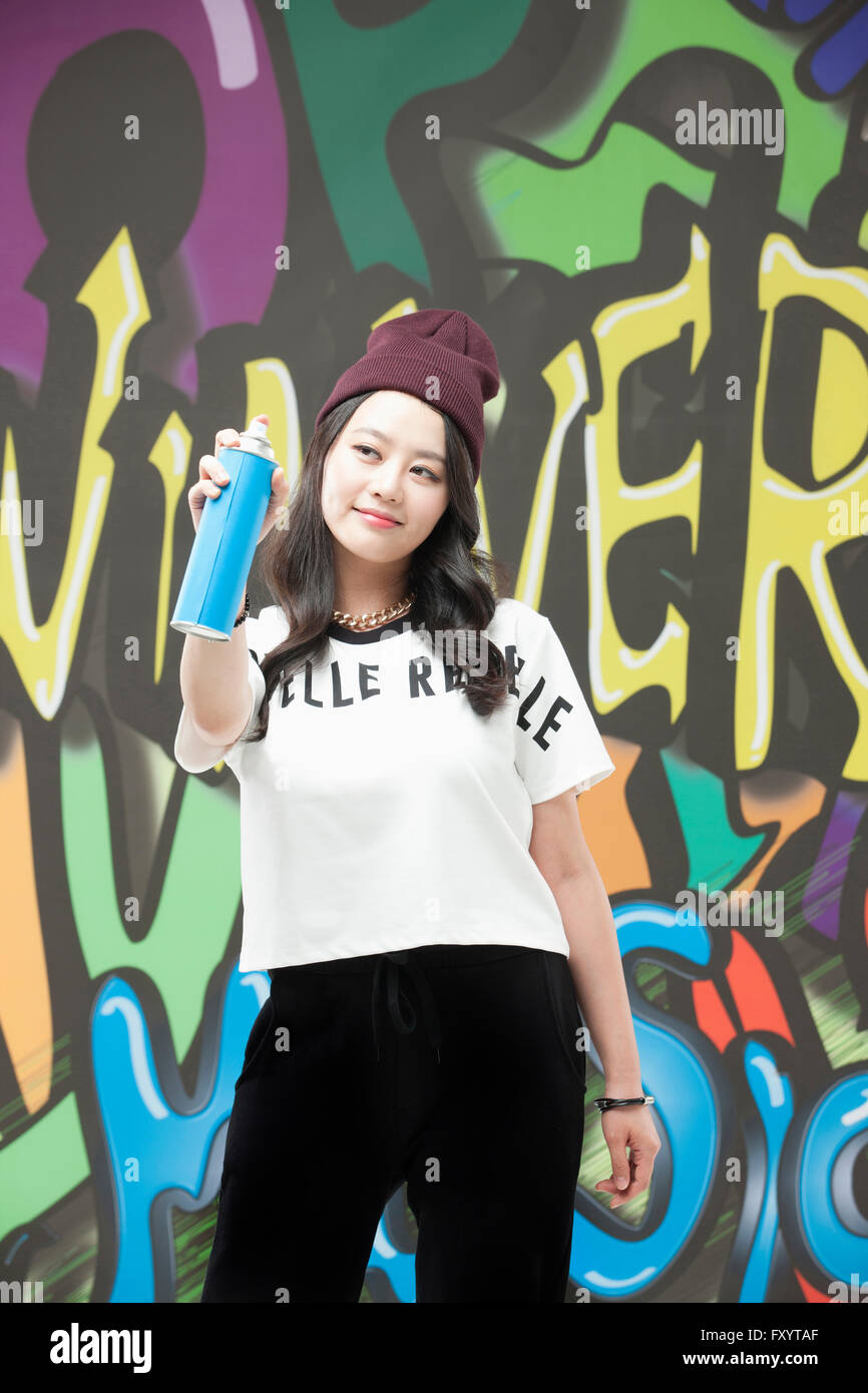 Jeune femme en tenue de style hip-hop une pulvérisation contre l'art du graffiti Banque D'Images