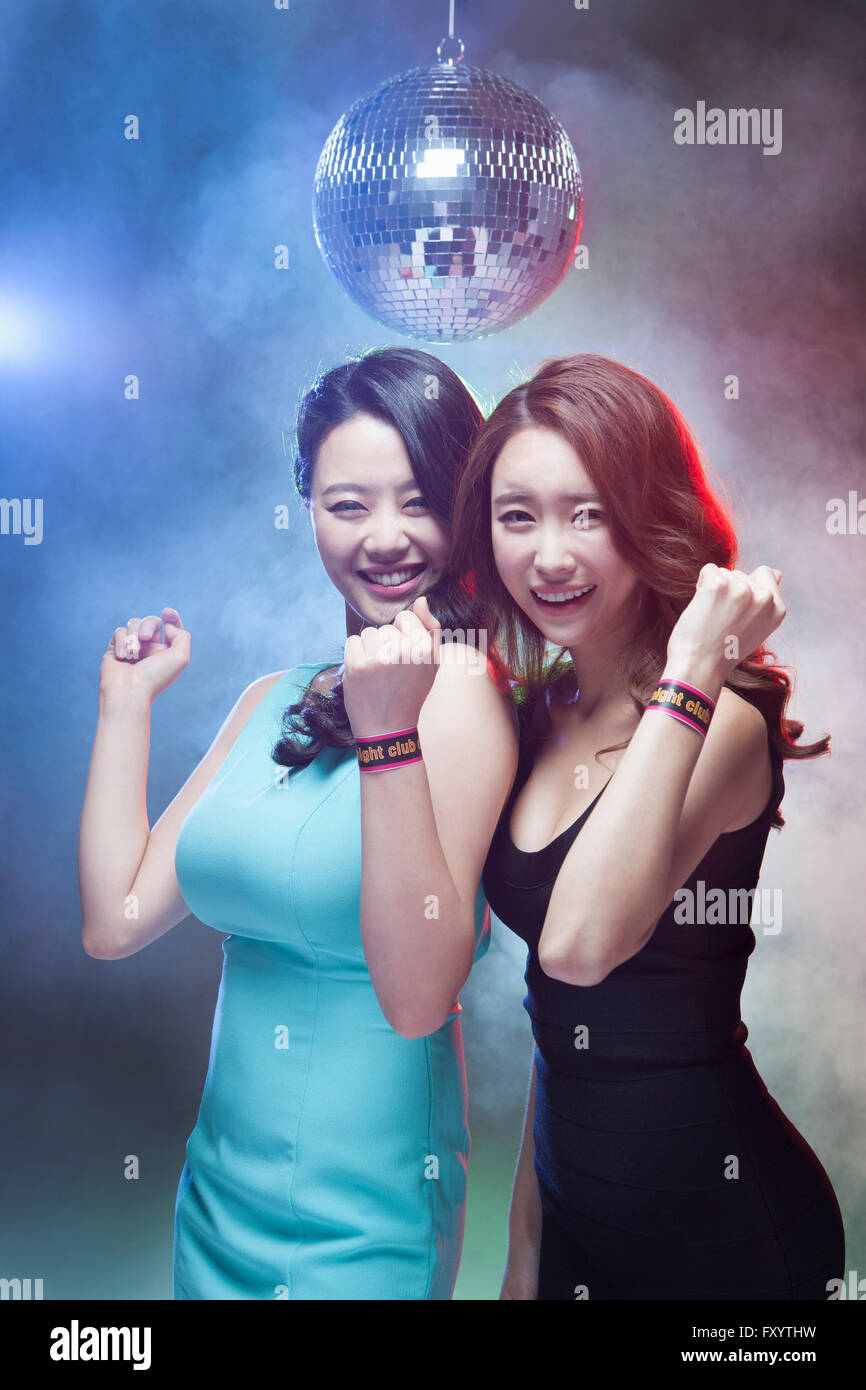Deux jeunes smiling women holding leurs poings à regarder/at nightclub Banque D'Images
