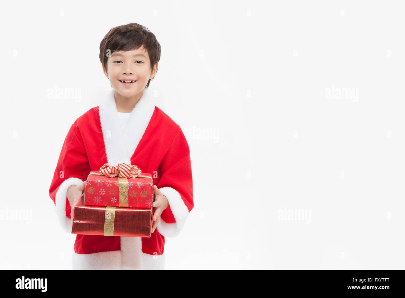 Portrait of smiling boy in Santa's clothes holding boîtes empilées à présenter avant Banque D'Images