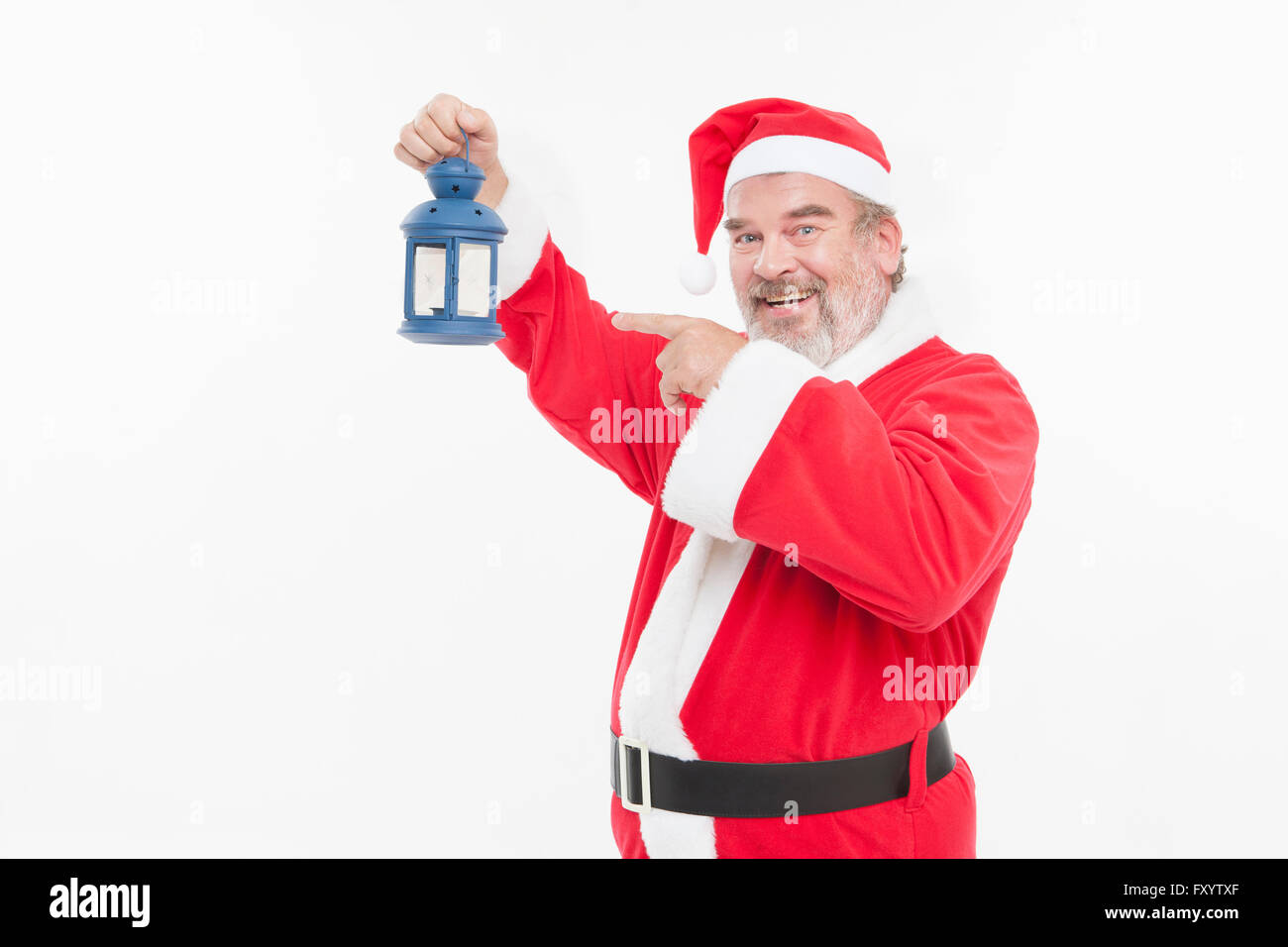 Portrait of smiling man dans la quarantaine avancée à Santa's clothes holding et pointant vers une lanterne à regarder/ Banque D'Images