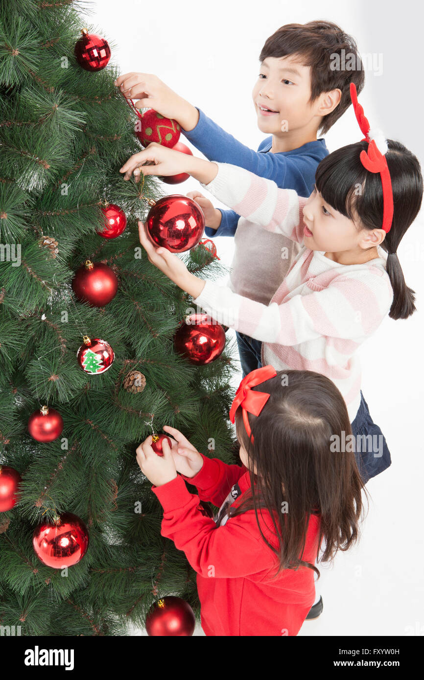 High angle vue de côté de smiling children decorating a Christmas Tree Banque D'Images